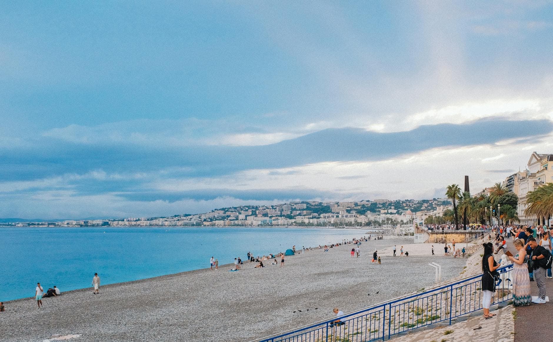 Lively beach scene in Nice, France with people enjoying the promenade.