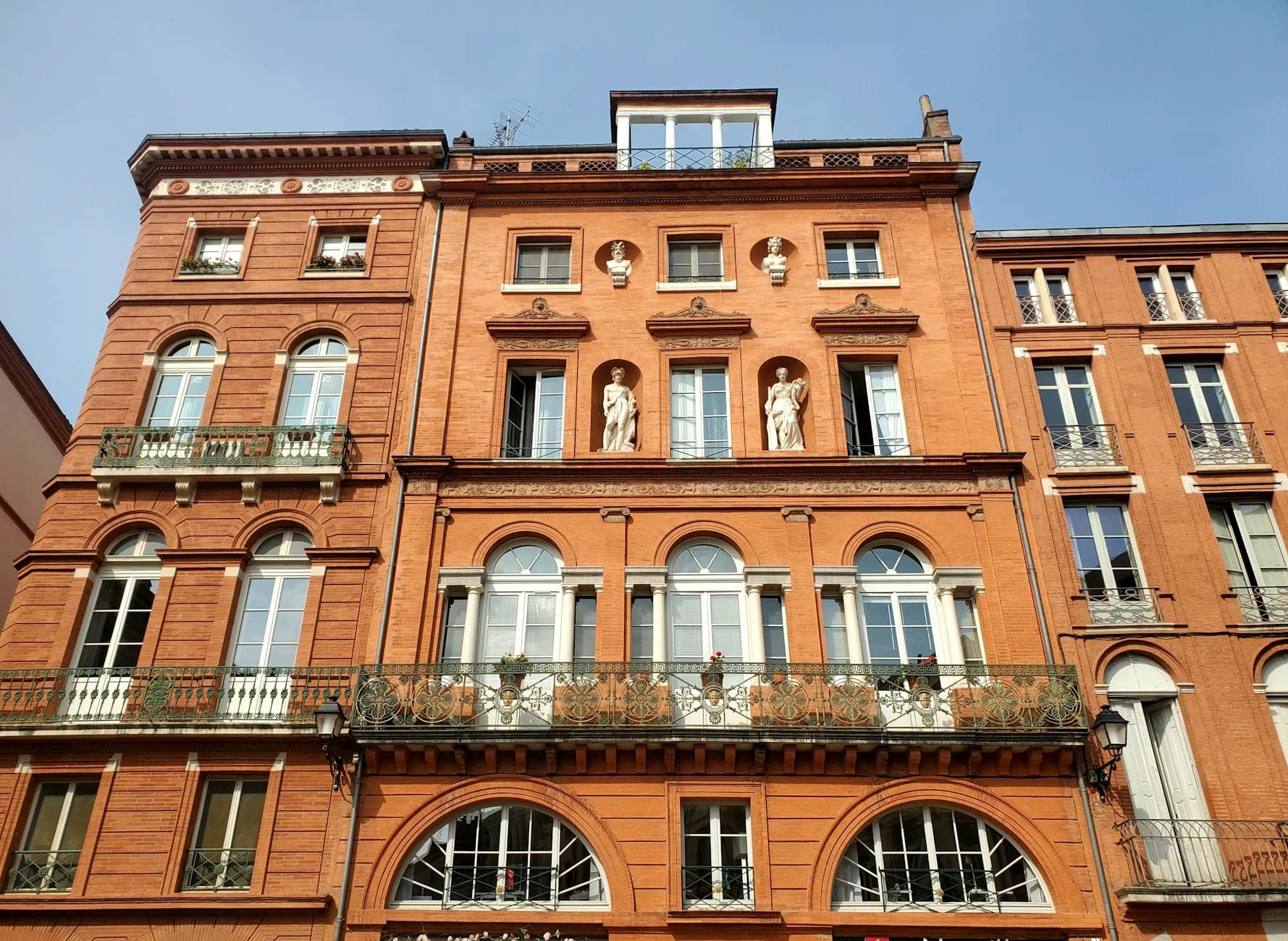 Red brick facade with classical architecture in Place de la Trinité, Toulouse.