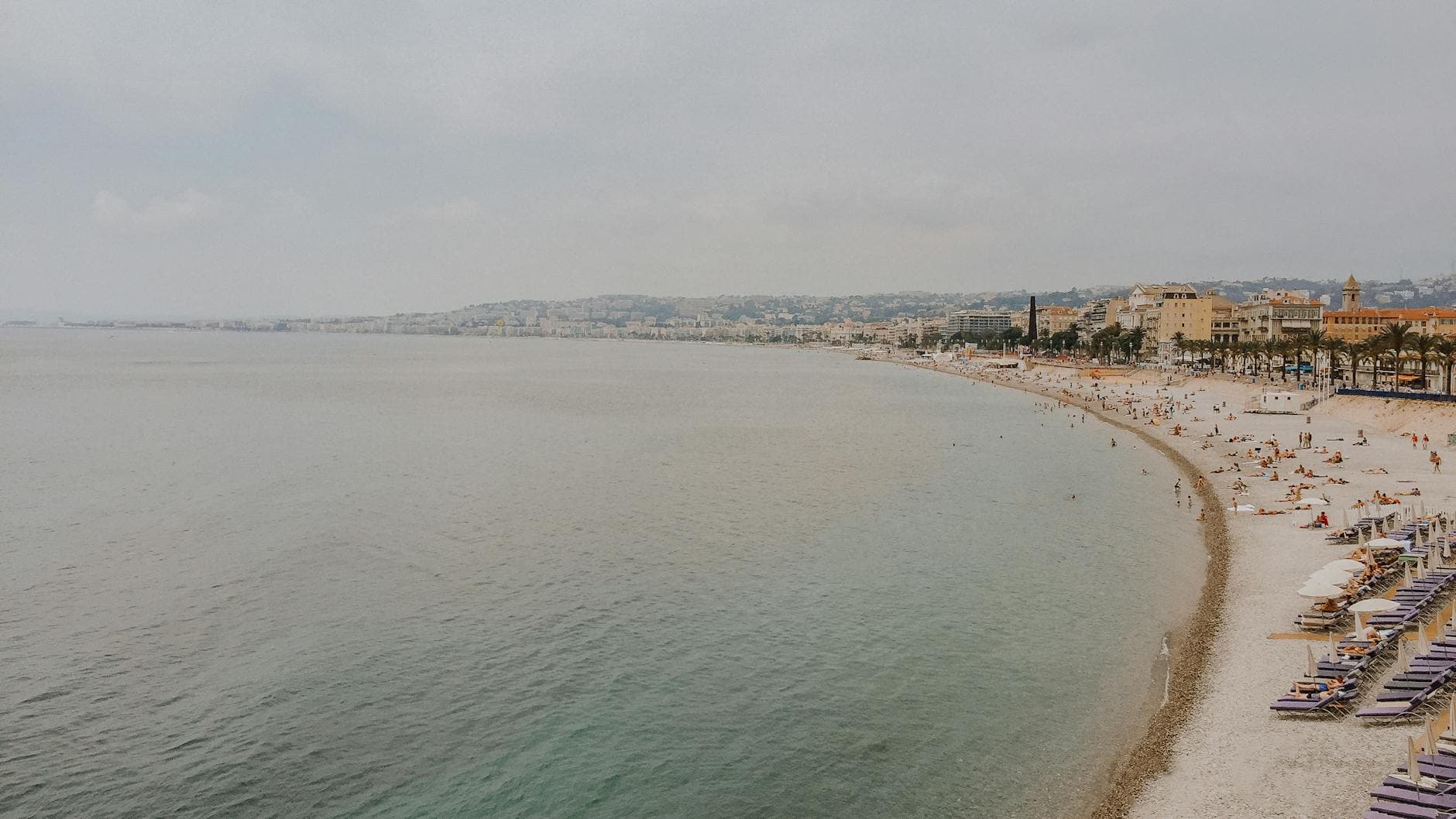 Aerial view of Nice's beachfront with azure waters and bright sandy shores, capturing the essence of summer leisure.