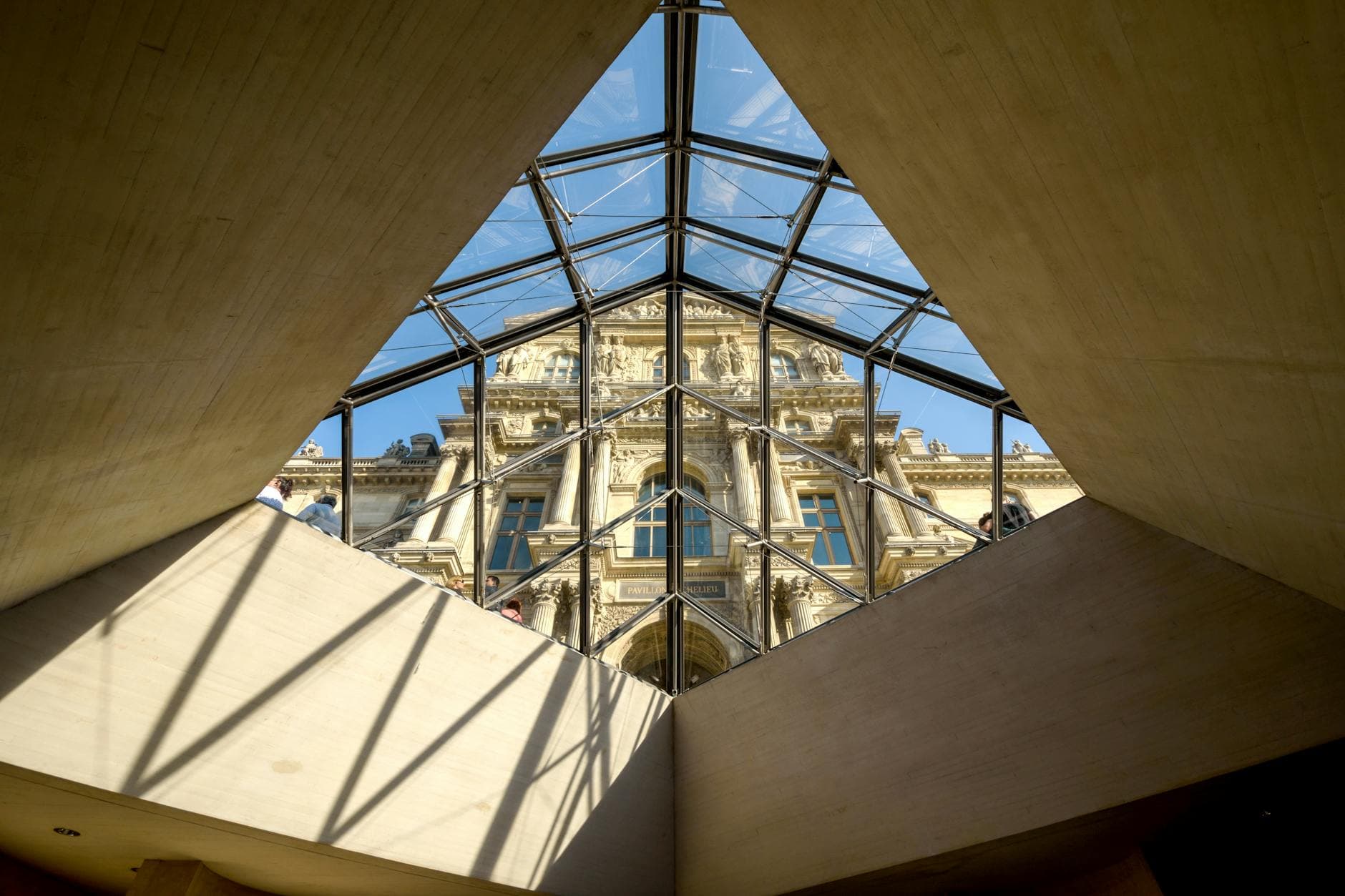 A stunning view of the Louvre Museum in Paris, seen through the geometric glass pyramid.