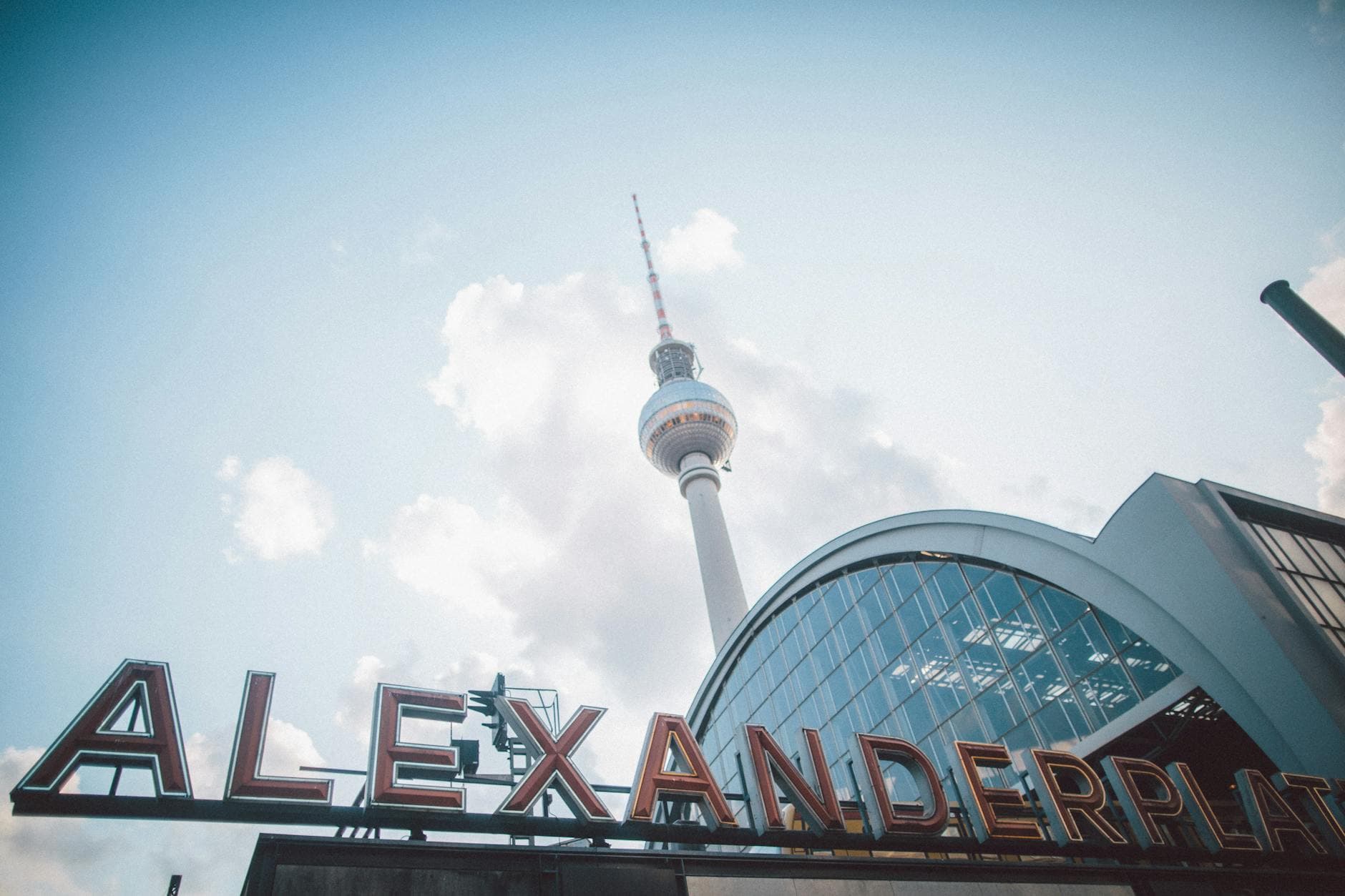 A striking low-angle shot capturing Berlin's TV Tower at Alexanderplatz against a cloudy sky.