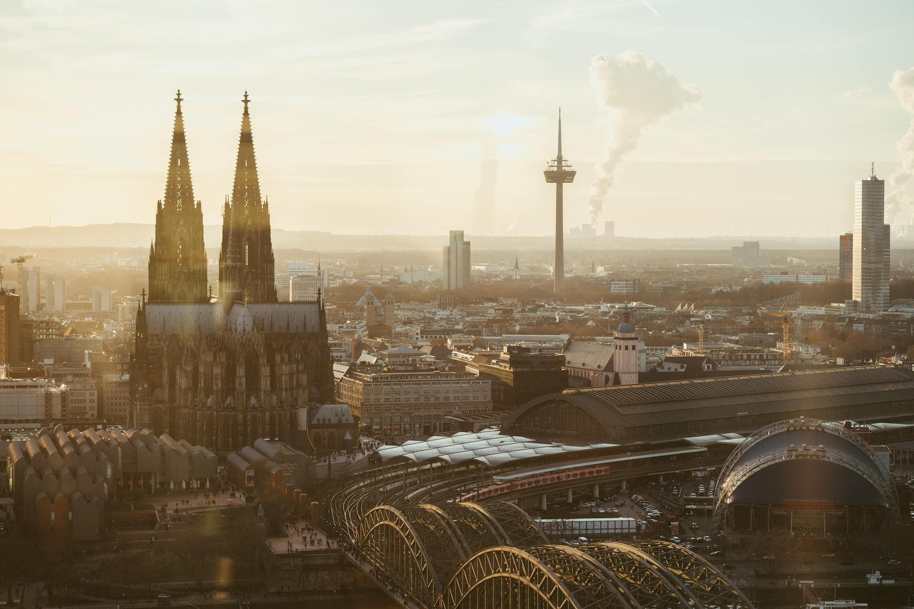 A breathtaking view of Cologne Cathedral at sunrise, surrounded by urban cityscape.