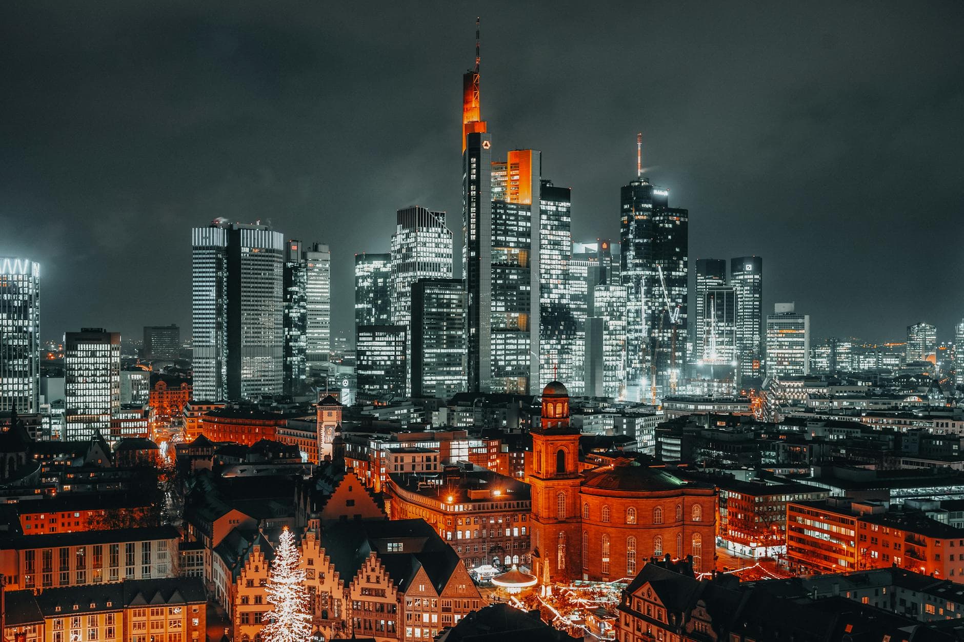 A stunning night view of Frankfurt's skyline featuring illuminated skyscrapers and historic buildings.