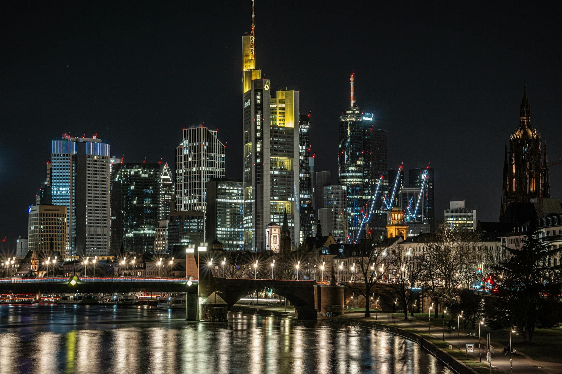 Stunning view of Frankfurt's skyline at night with illuminated skyscrapers reflected in the Main River.