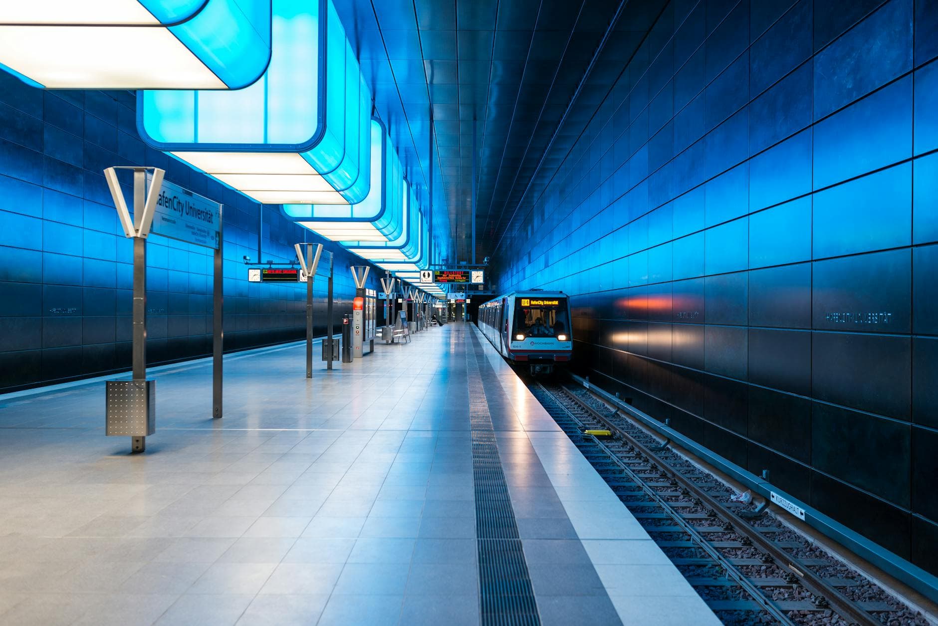 Blue-lit subway station in Hamburg showcasing modern architecture and public transport.