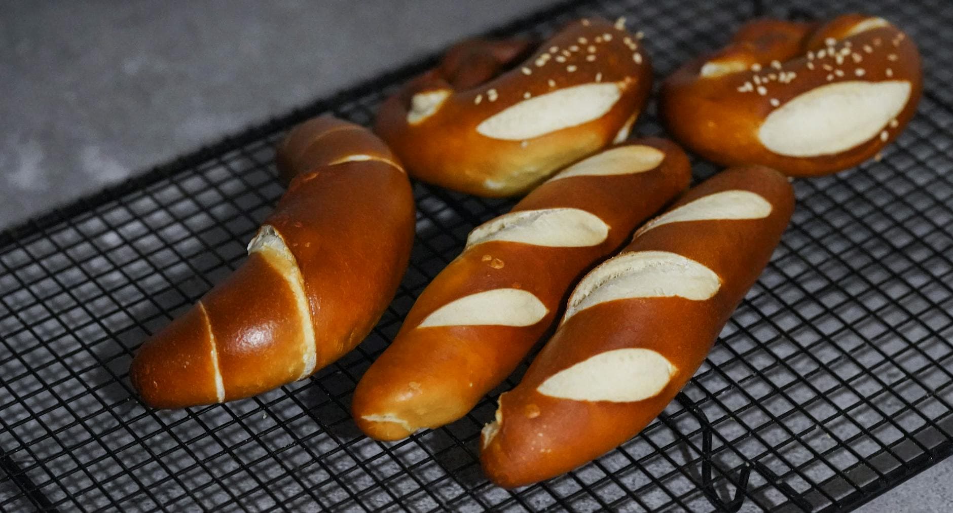 Close-up of freshly baked Bavarian pretzels cooling on a rack, showcasing their golden-brown texture.
