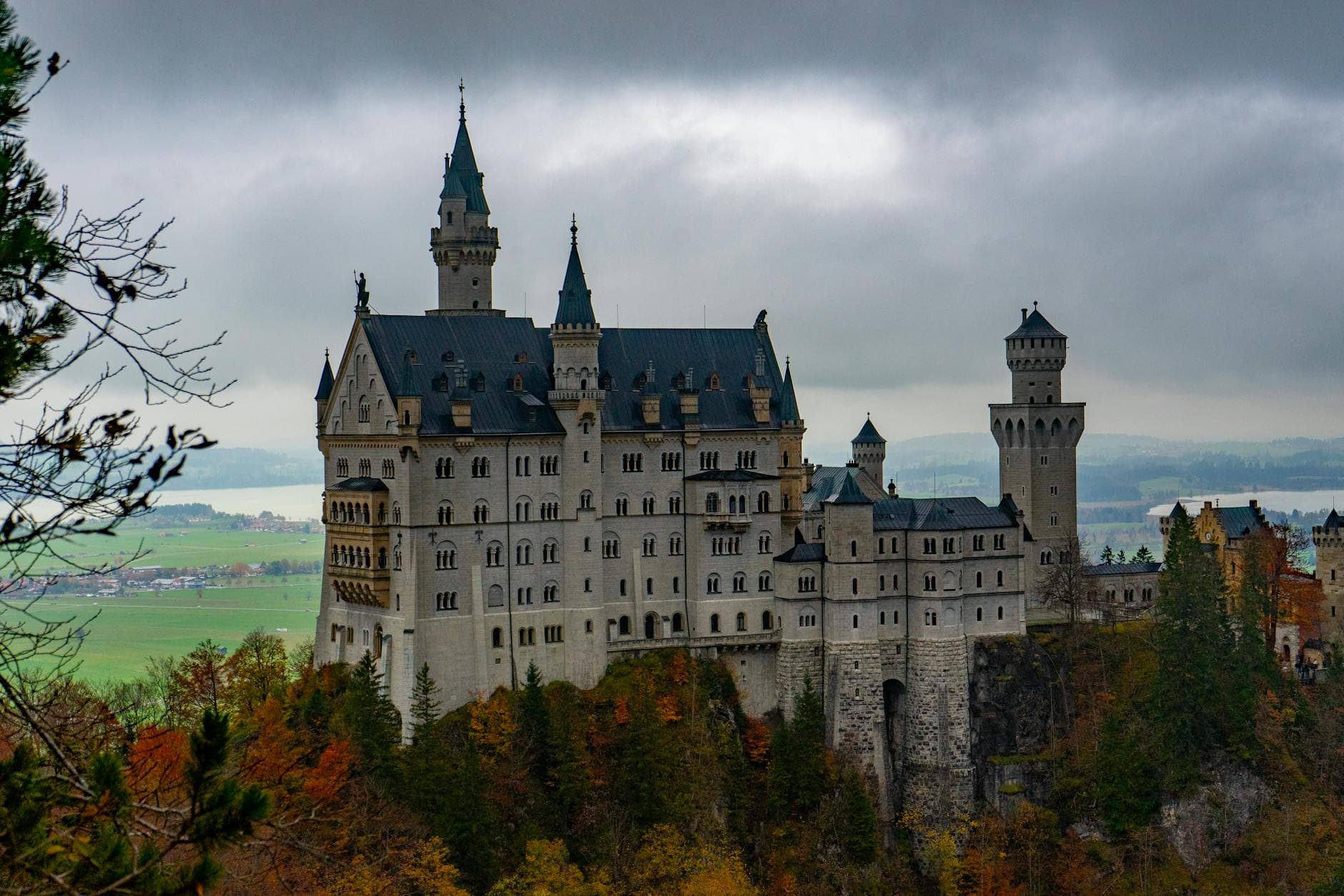 Dramatic view of Neuschwanstein Castle amidst colorful autumn foliage in Bavaria, Germany.