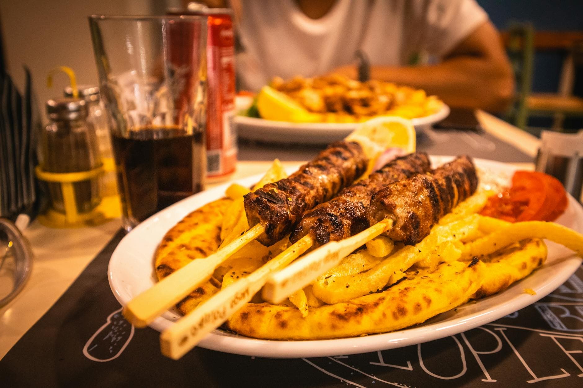 Tasty grilled meat skewers served with fries and pita bread, perfect for a hearty meal.