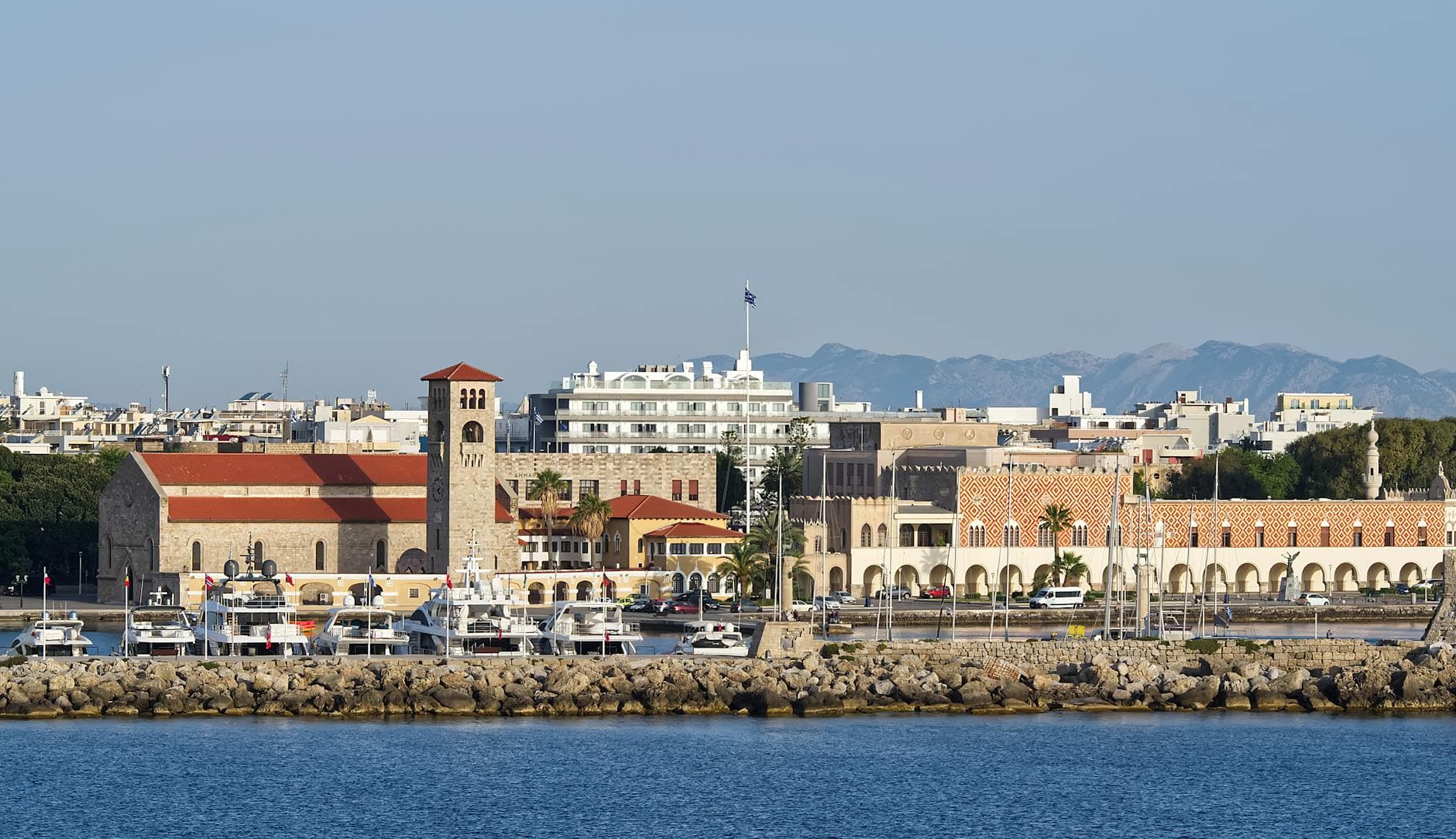 Mandraki Harbor with yachts and medieval architecture in Rhodes, Greece during daytime.