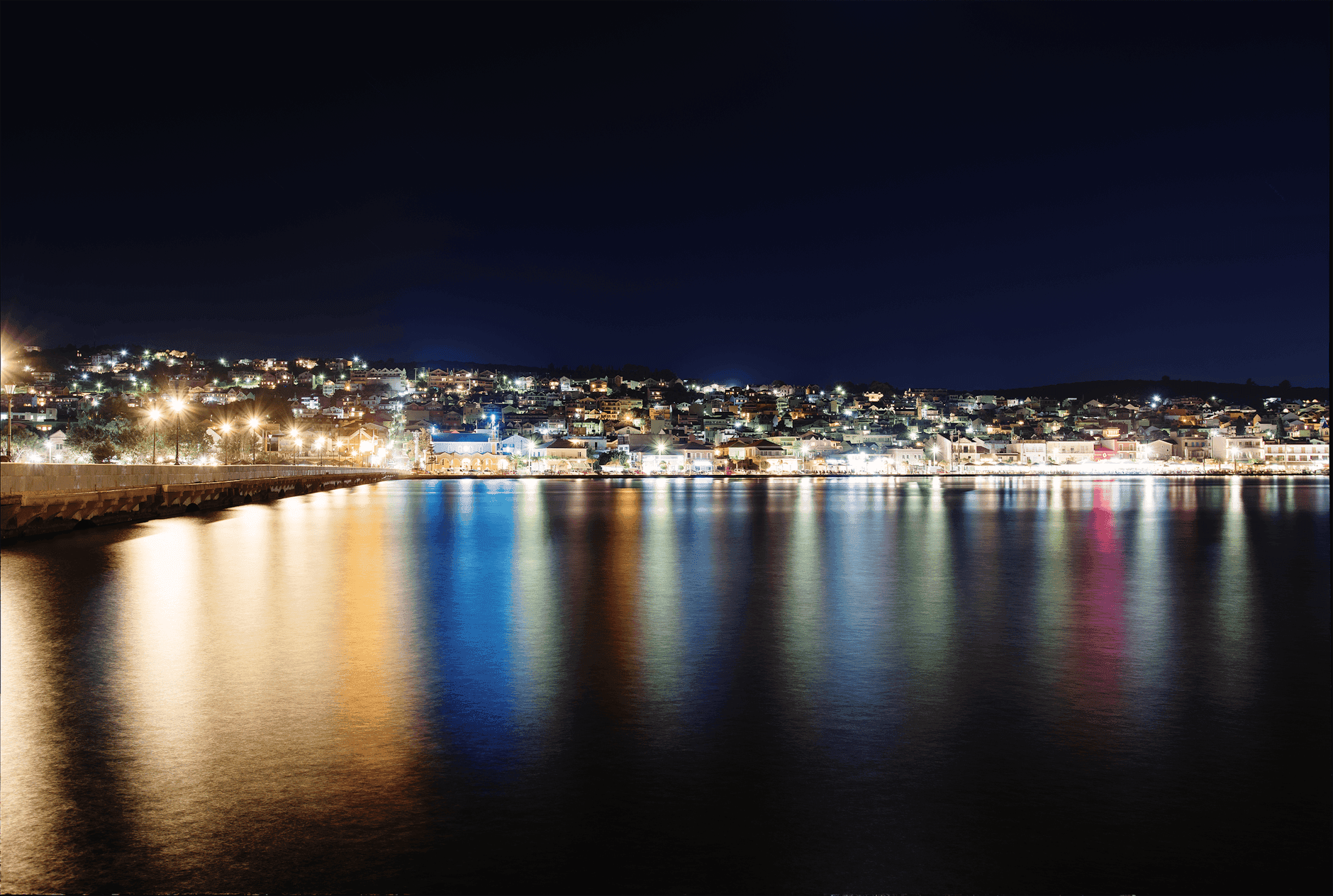 Picturesque night view of Argostoli with illuminated waterfront and reflections.