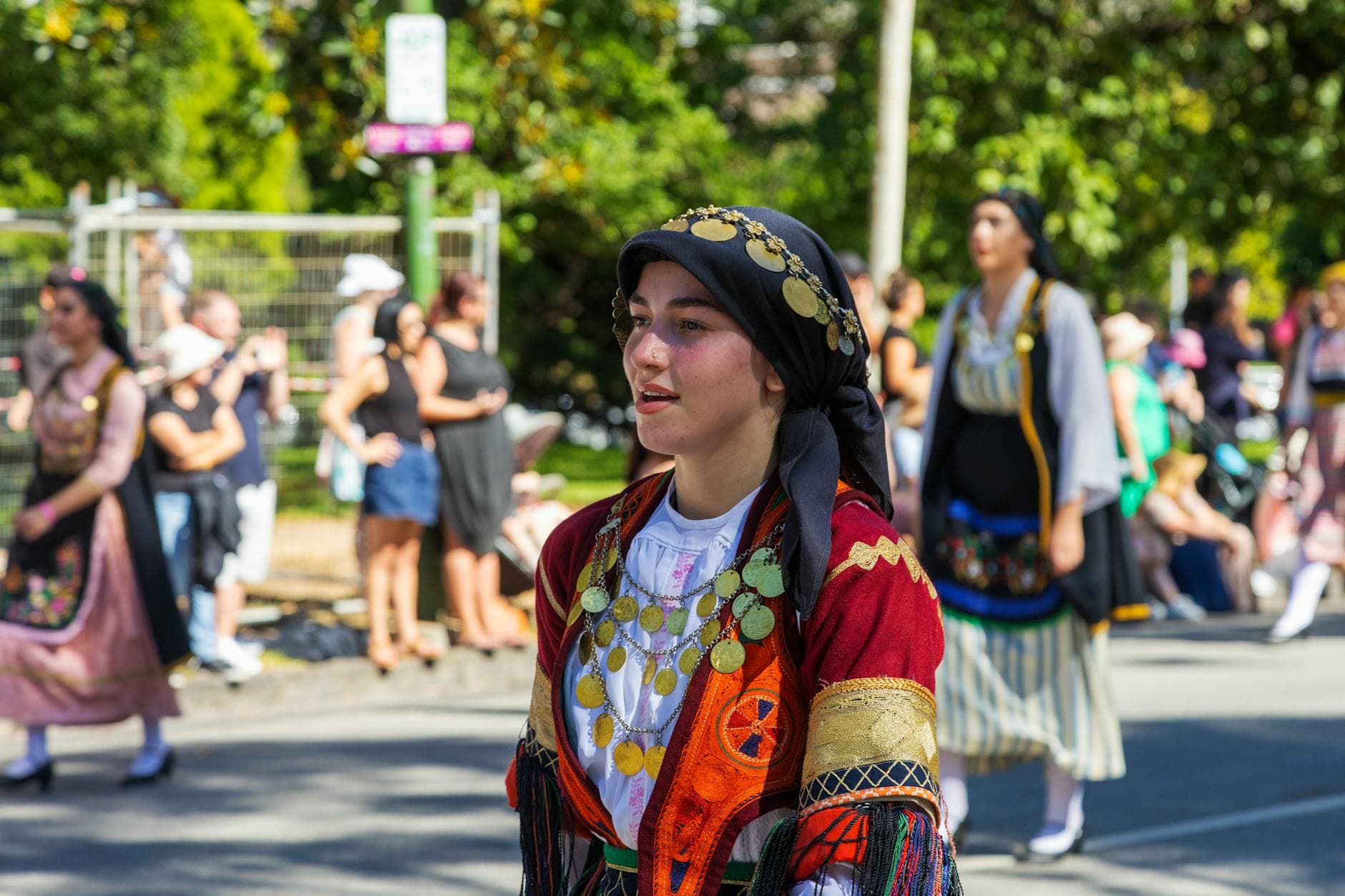 Woman wearing Greek traditional clothing participates in a vibrant outdoor parade.