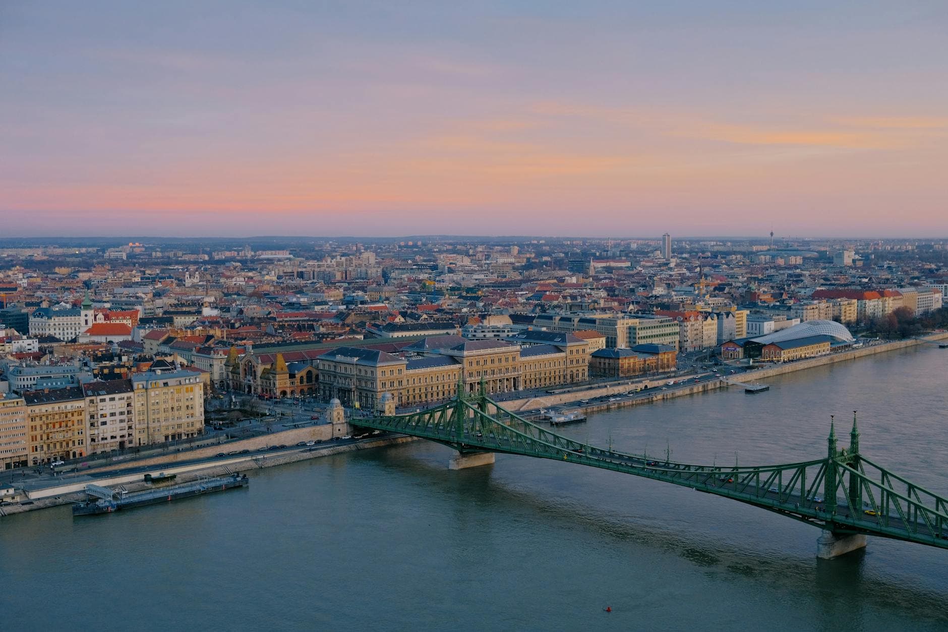 Aerial view of Liberty Bridge and Budapest skyline over the Danube River during sunset.