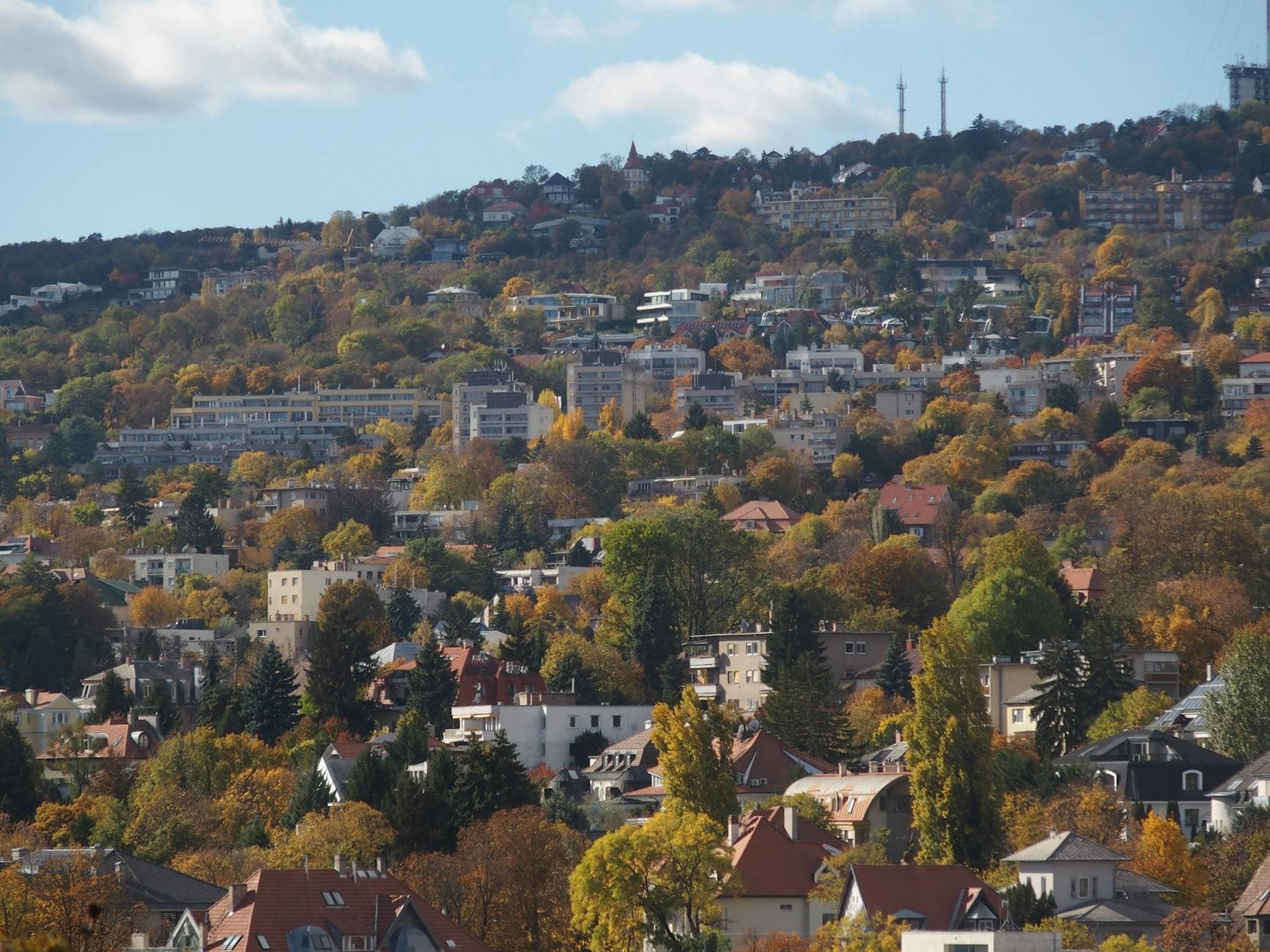 Scenic view of a hillside town in autumn with colorful fall foliage and residential houses.