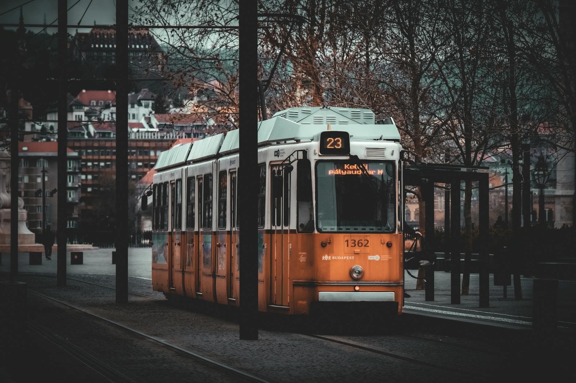 Orange tram at dusk with historic Budapest architecture in the background.