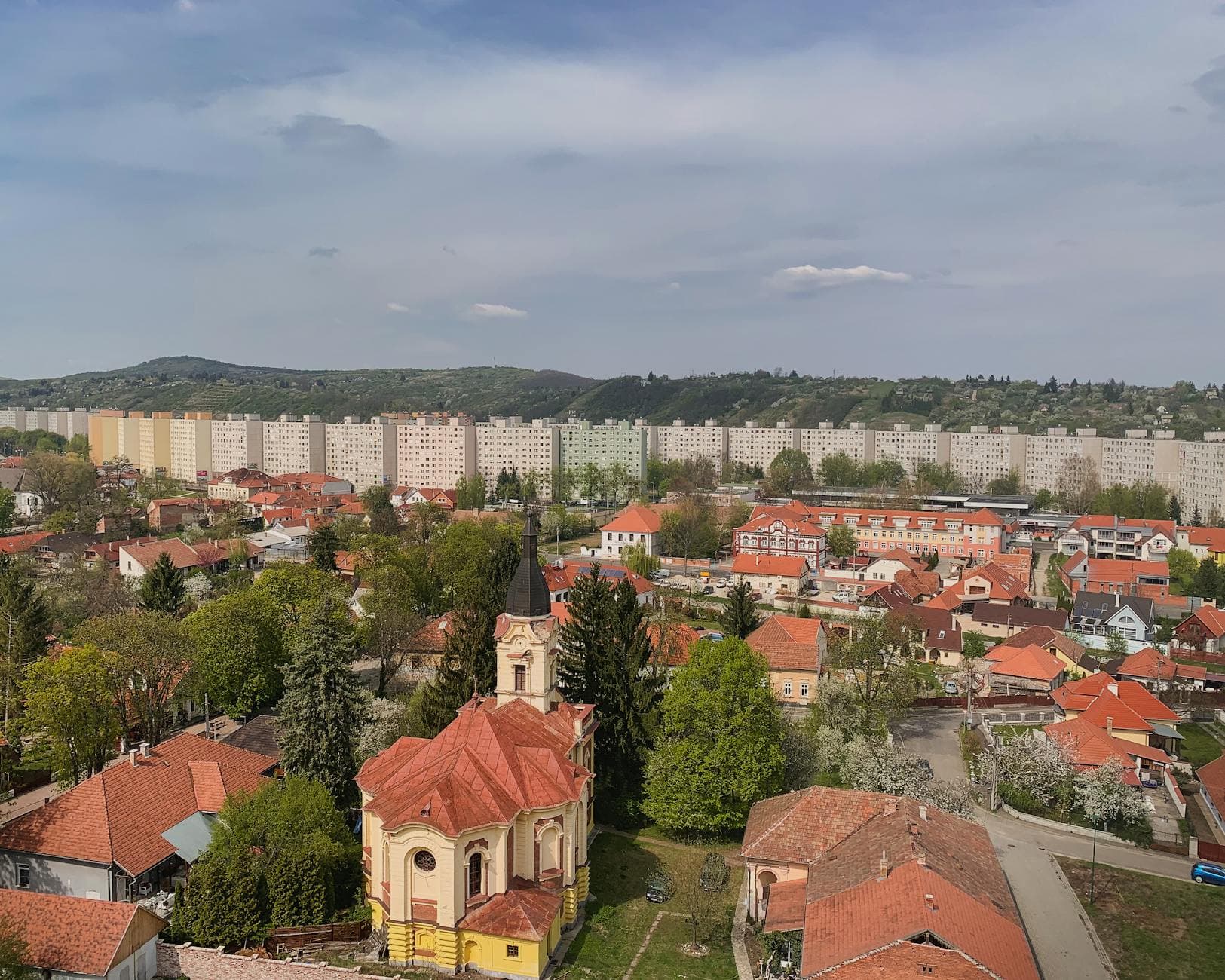 Aerial view of Miskolc, Hungary showcasing apartment buildings, lush greenery, and urban landscape.
