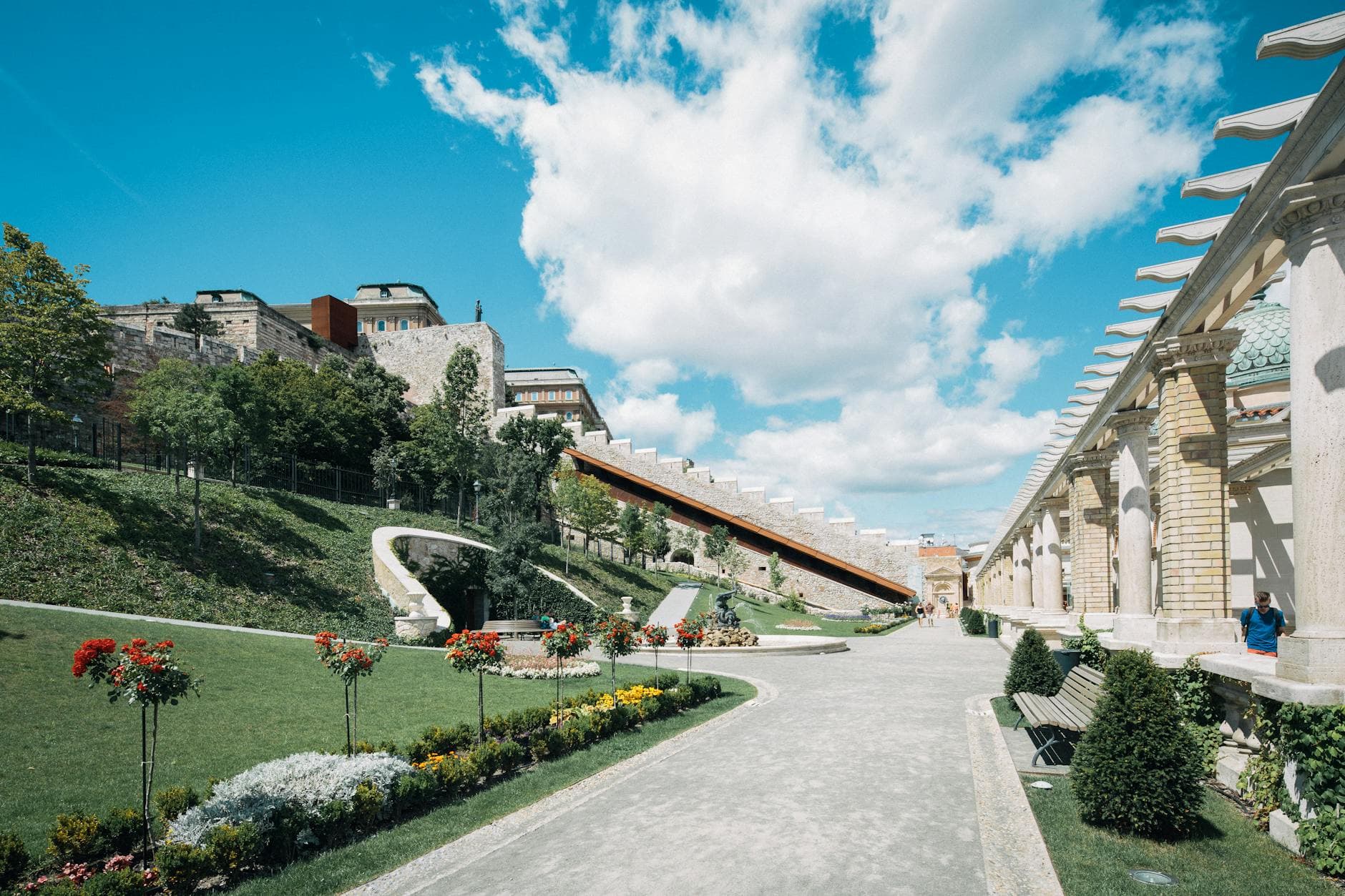Vibrant garden scene in Budapest showcasing historic architecture and a beautiful blue sky.