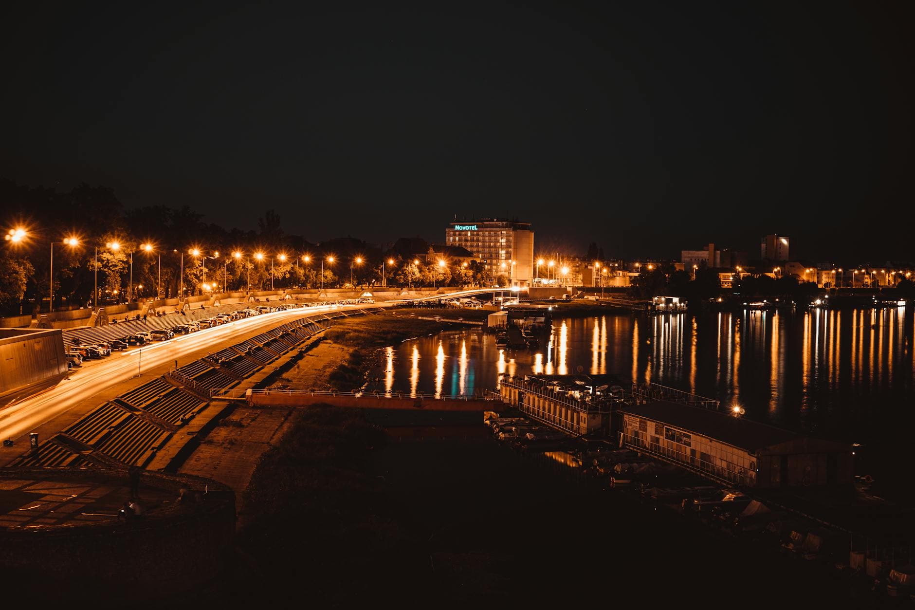 Stunning aerial view of Szeged at night showcasing illuminated streets and reflections on the waterfront.