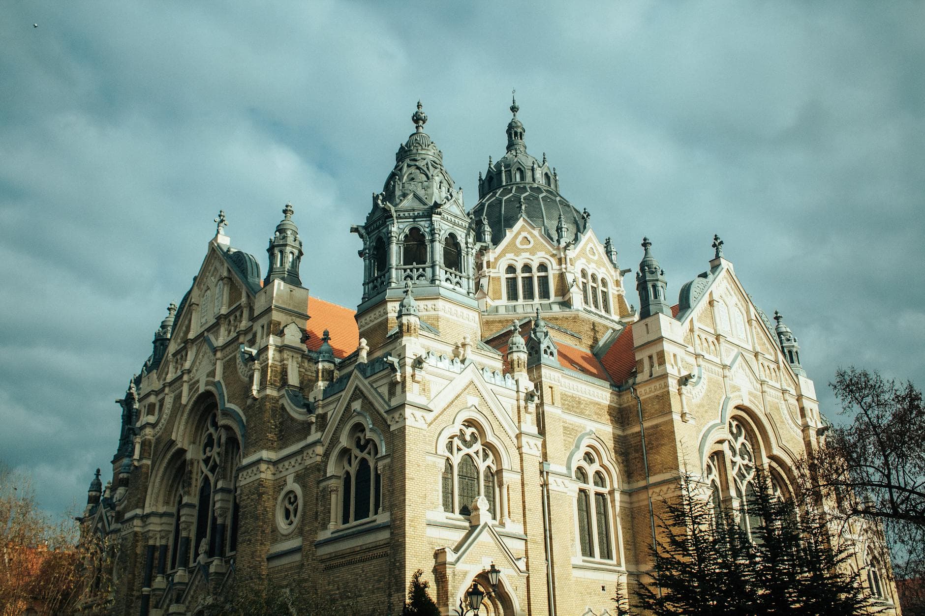 Capture of the stunning architectural detail of the New Synagogue under a cloudy sky in Szeged, Hungary.