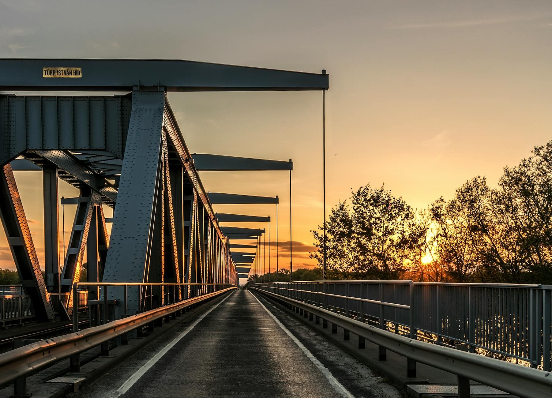 A picturesque view of a steel bridge at sunset, highlighting the vibrant colors of dusk and nature.