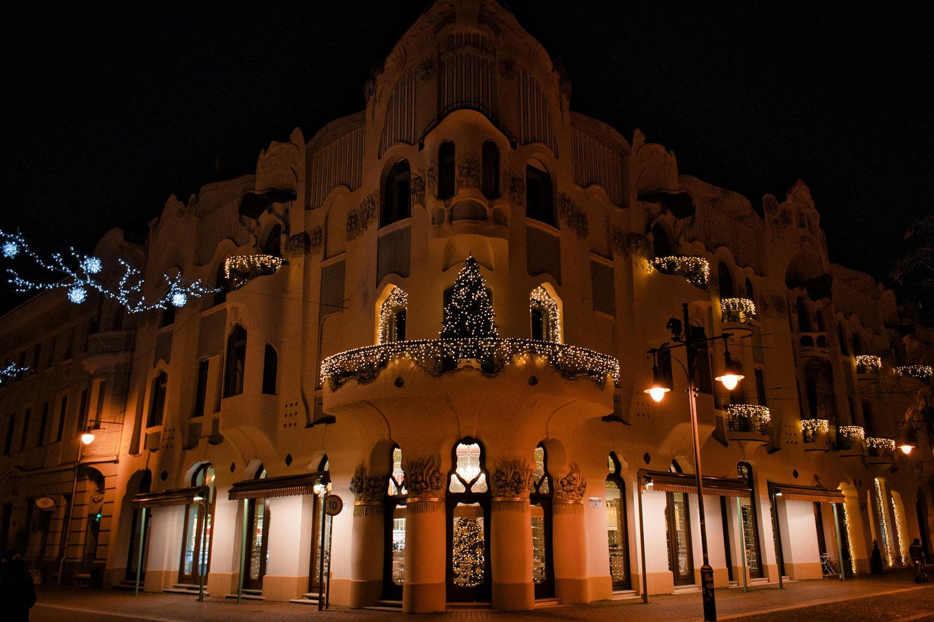 Night view of a beautifully lit Art Nouveau building decorated with Christmas lights in Szeged, Hungary.