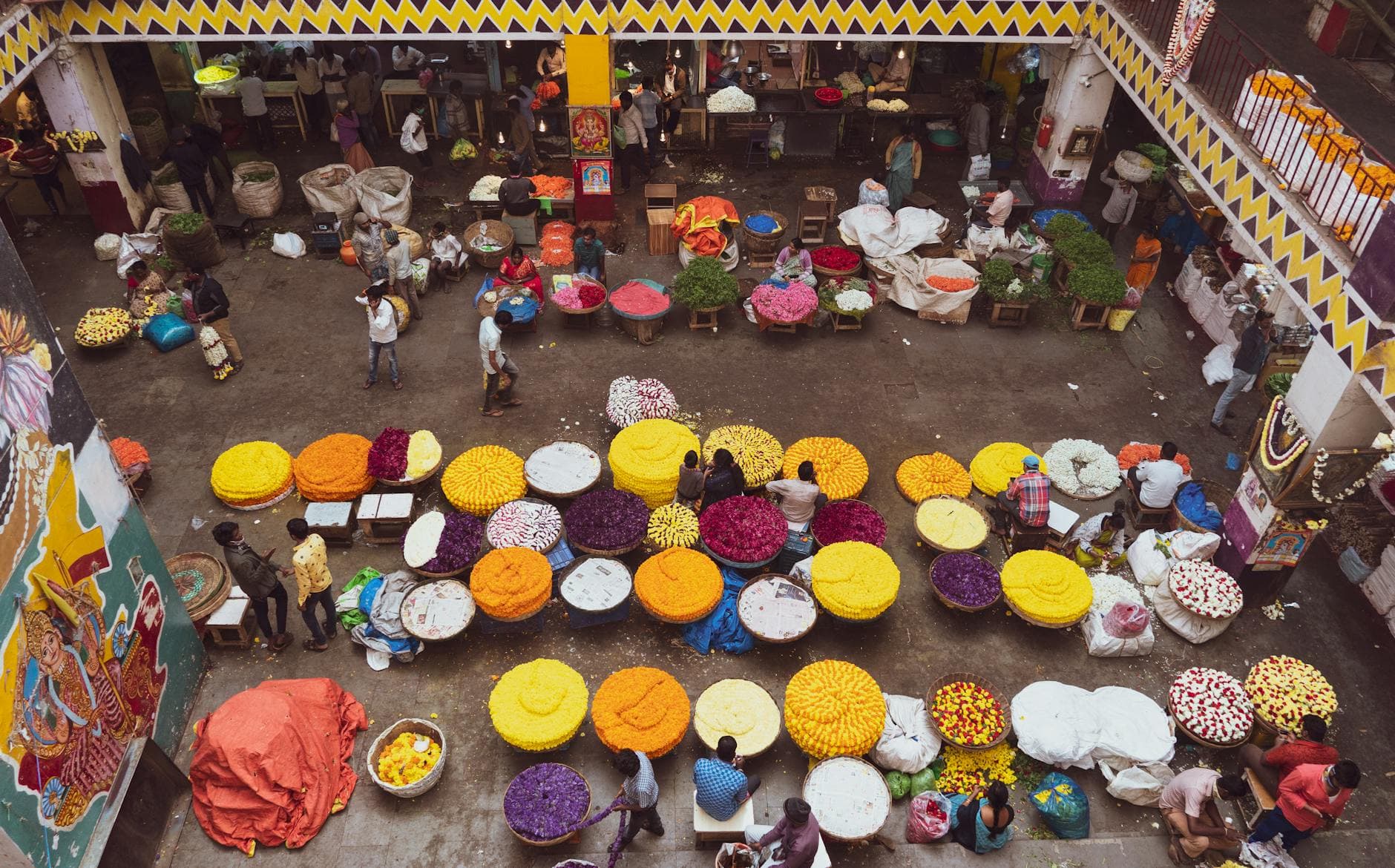 Aerial view of colorful flower stalls at KR Market, Bengaluru, showcasing local vendors and lively atmosphere.