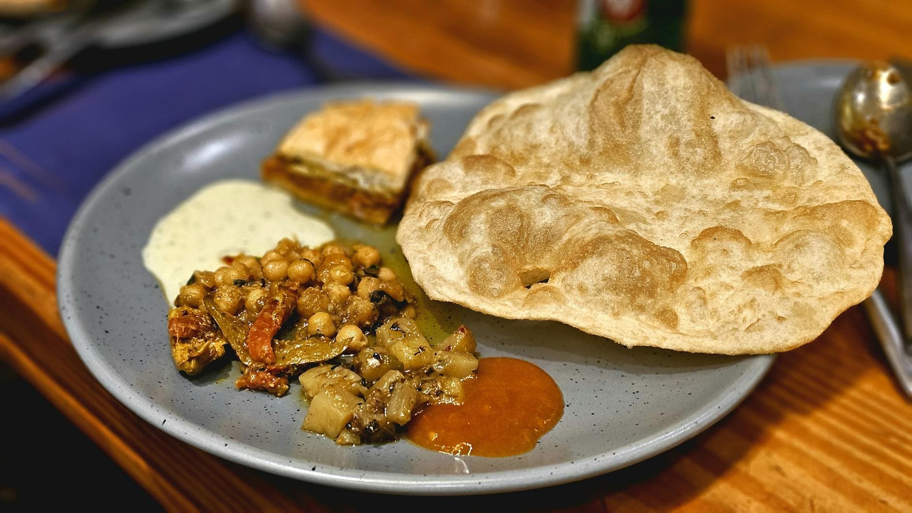 A delicious Indian meal featuring puri, chole, and chutneys served on a blue plate.