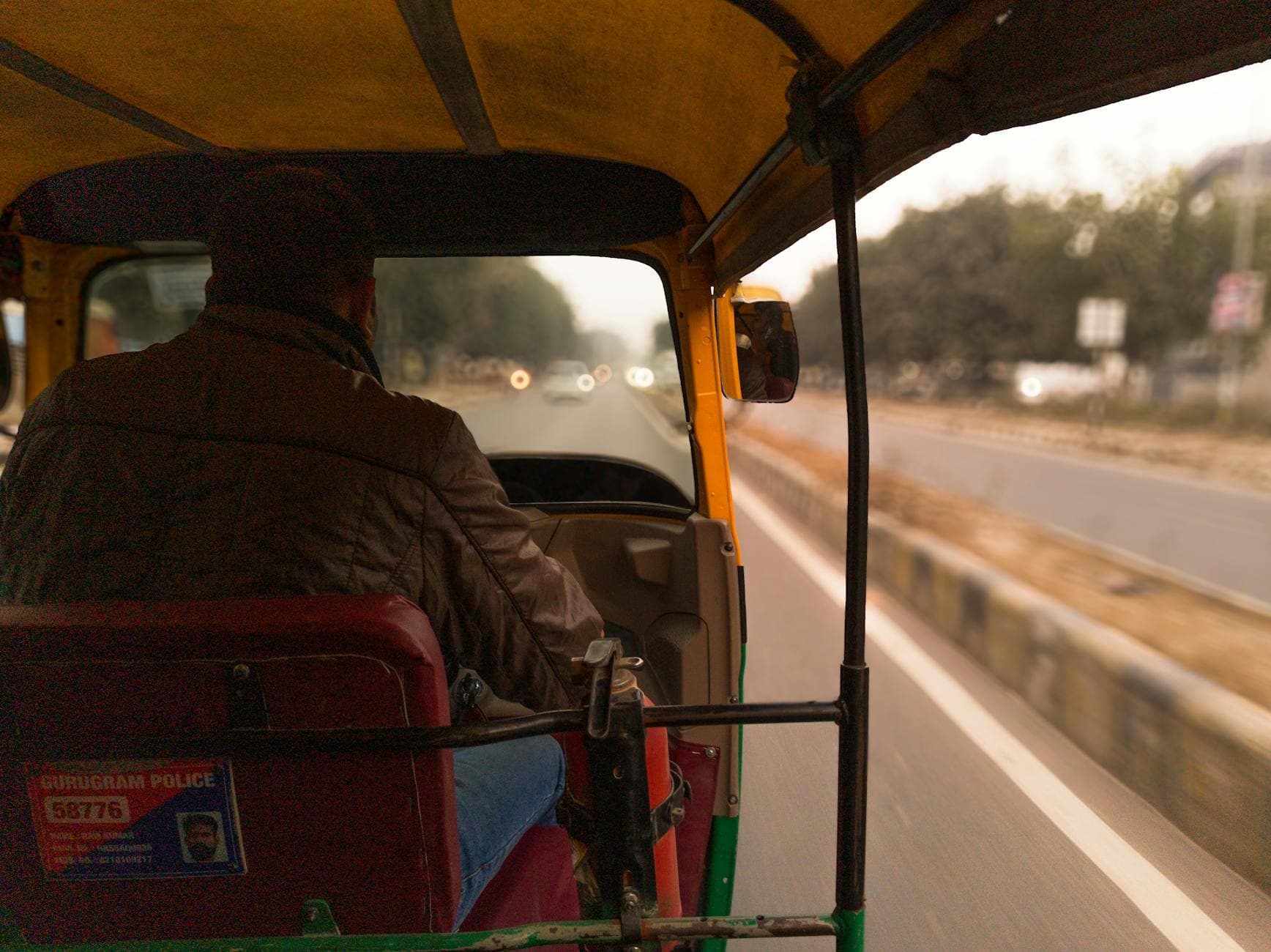 Inside view of a moving autorickshaw on Gurugram road, capturing urban dynamics.