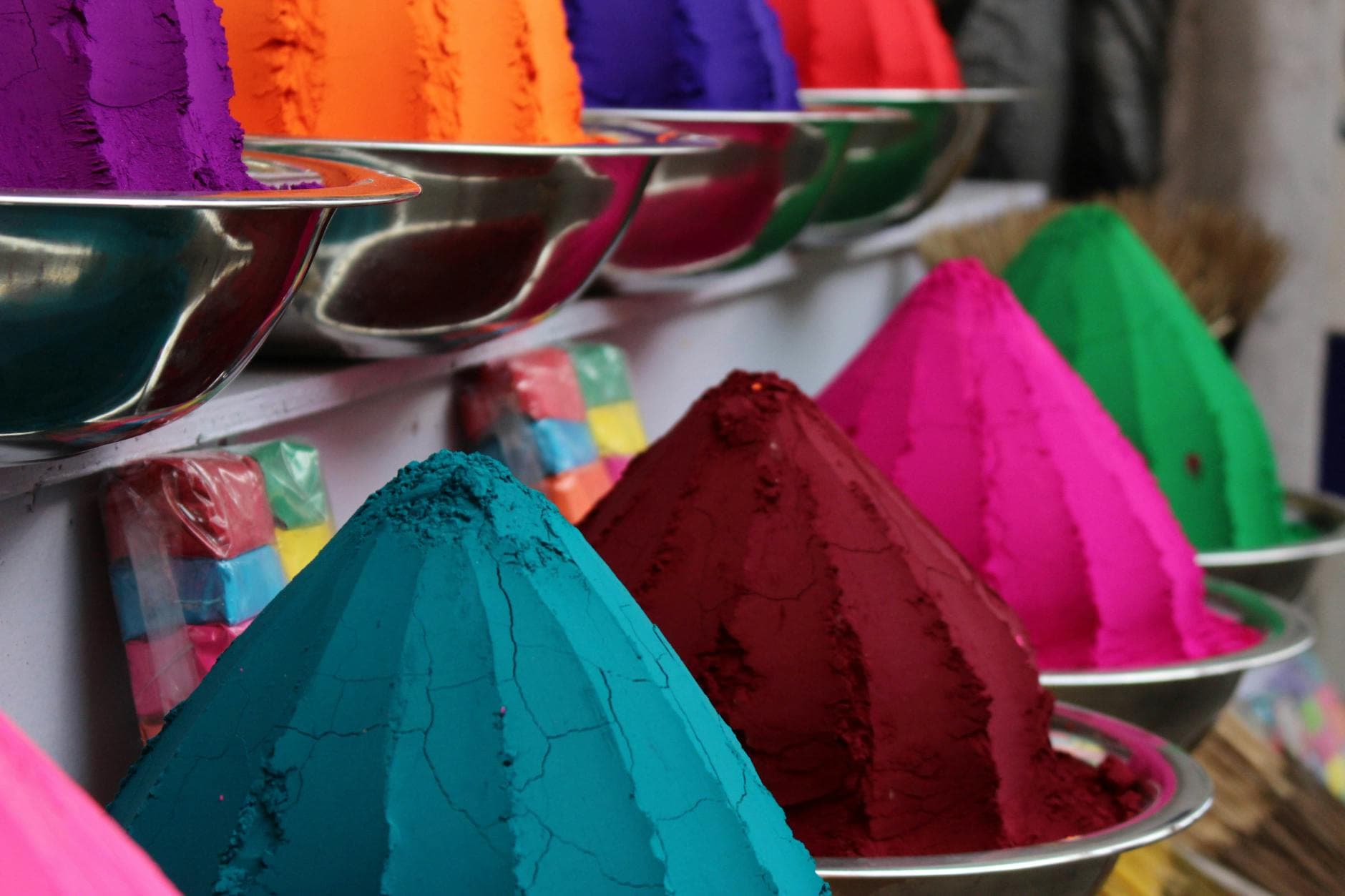 Close-up of vibrant colored powders in bowls at a market in Kochi, India.