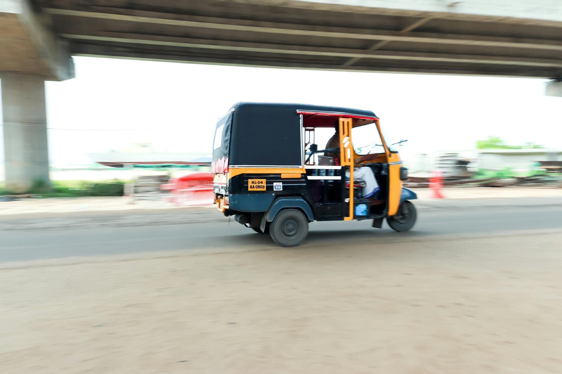 Auto rickshaw driving on a busy road in Kochi, Kerala, showcasing motion blur and speed.