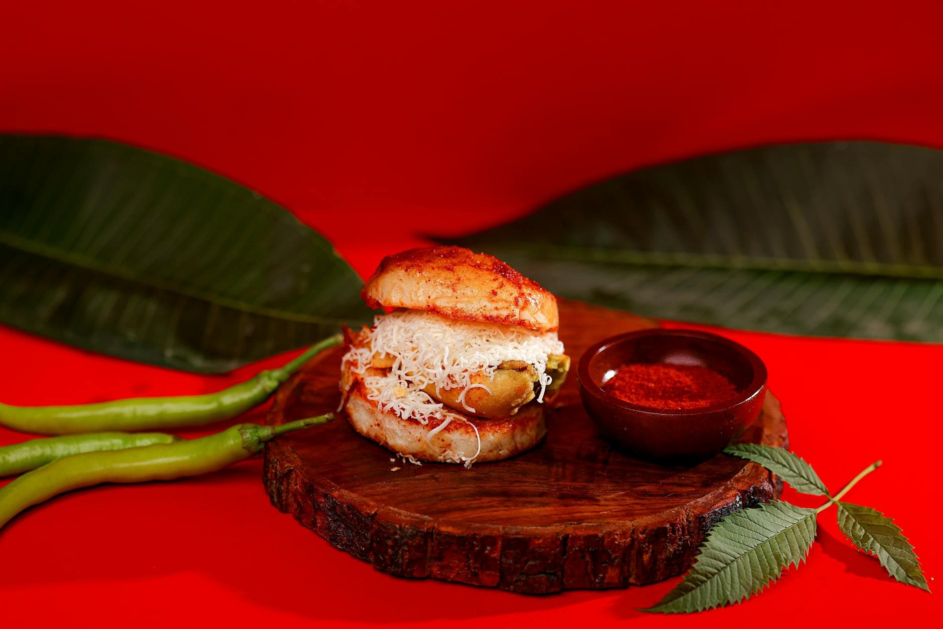 Traditional Indian vada pav garnished with green chilies and spicy chutney, perfect street food.
