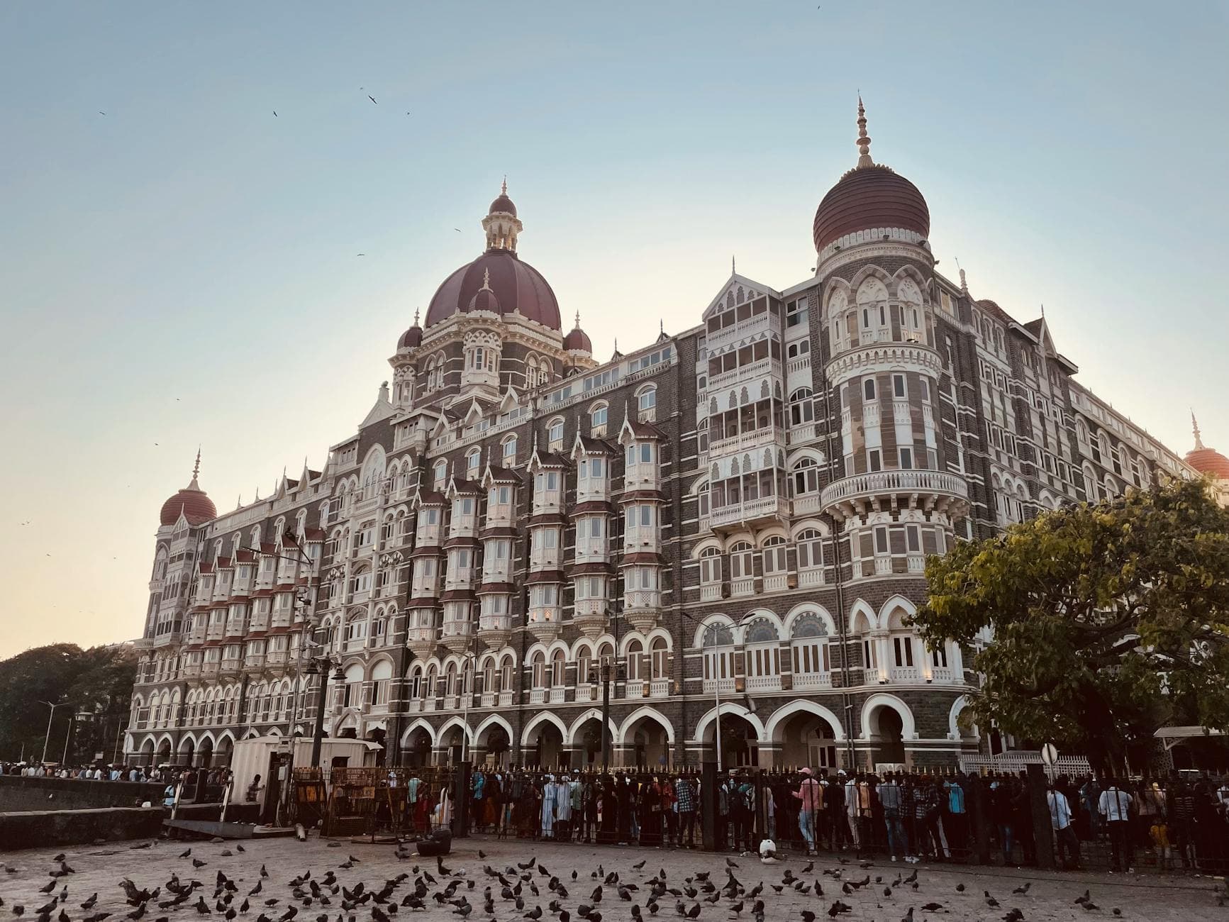 Iconic Taj Mahal Palace Hotel in Mumbai, captured during a warm evening, showcases ornate architecture.