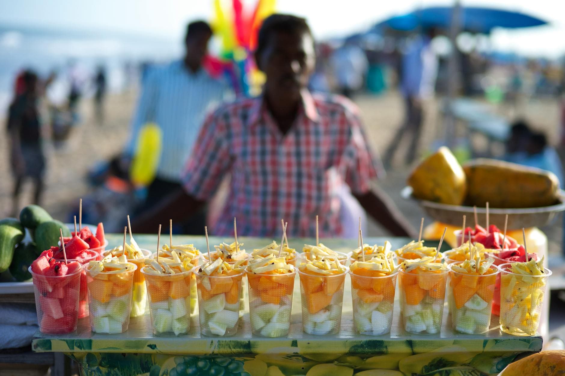 Vibrant tropical fruit stall with fresh cut fruits at a busy Chennai beach market.