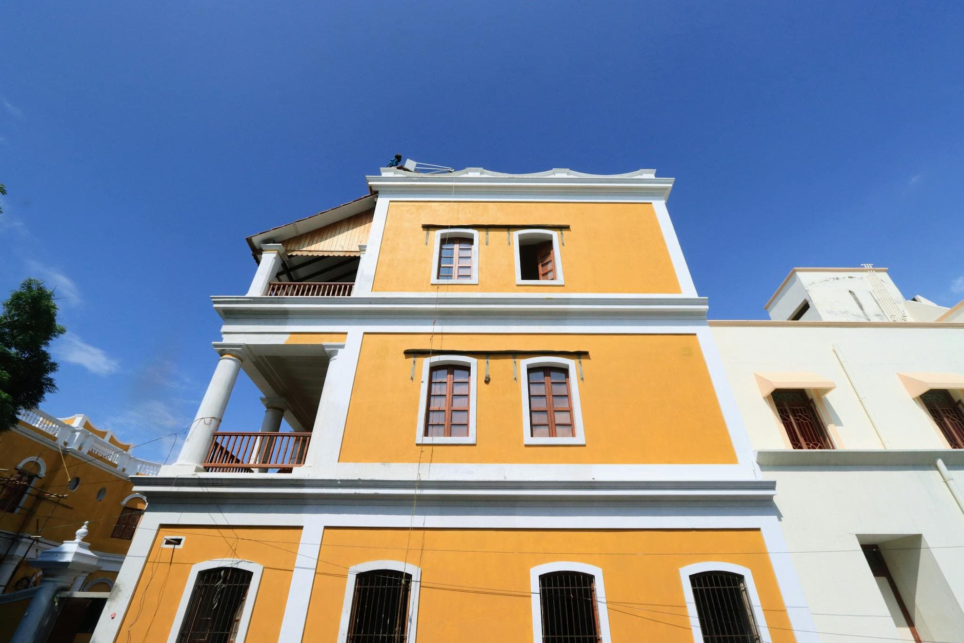 Vibrant yellow colonial building with tall columns under a bright blue sky, showcasing classic architectural style.