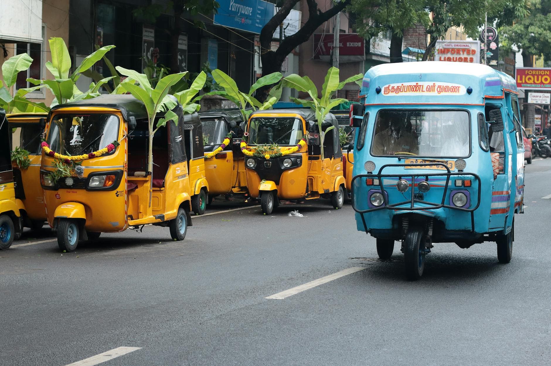 Colorful auto rickshaws adorned with decorations on a bustling street in Puducherry, India.