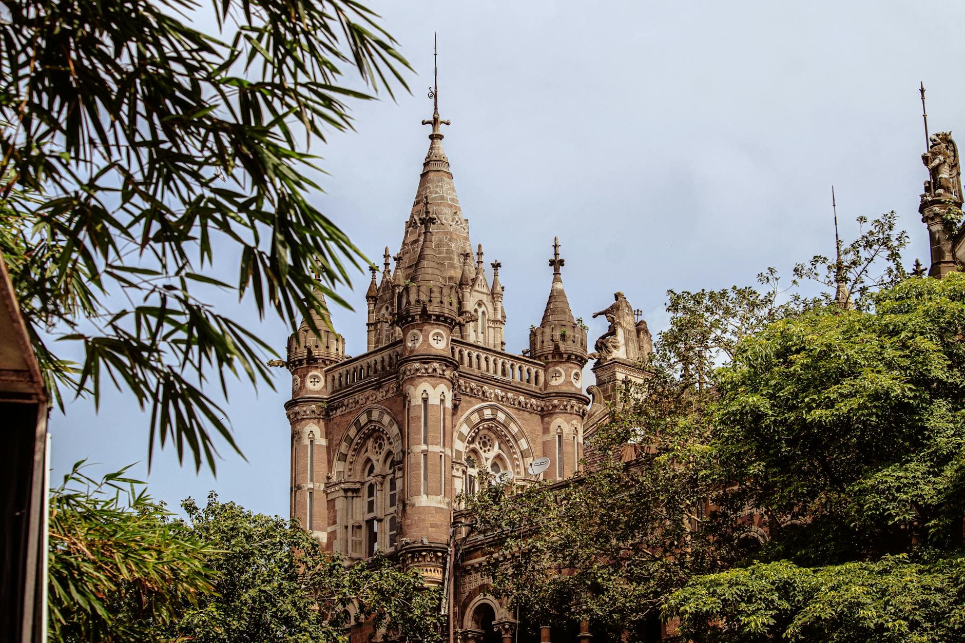 Stunning Victorian Gothic structure amidst lush greenery in Mumbai, India.