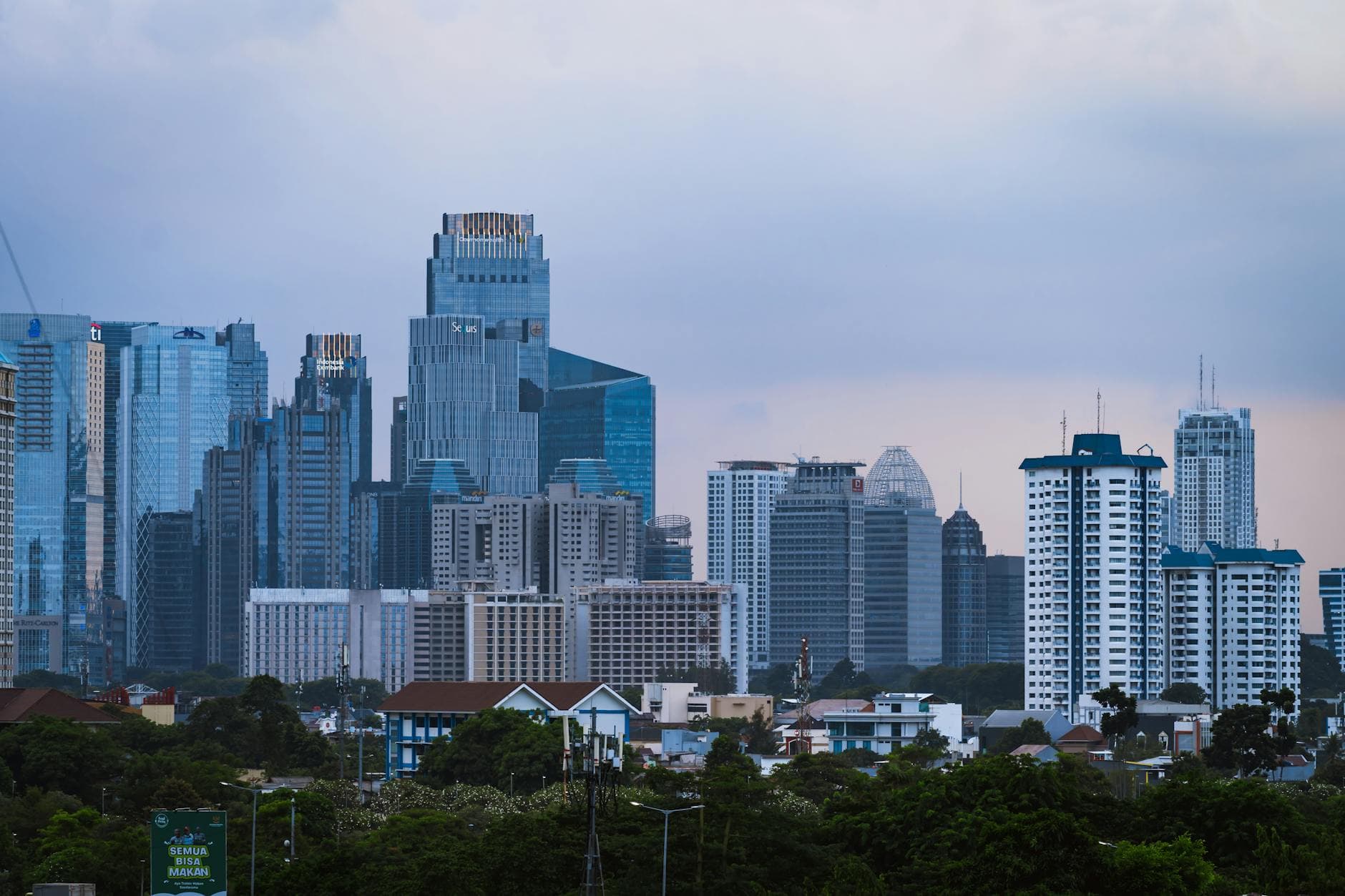 Discover Jakarta's dynamic skyline, featuring modern skyscrapers under a blue sky.