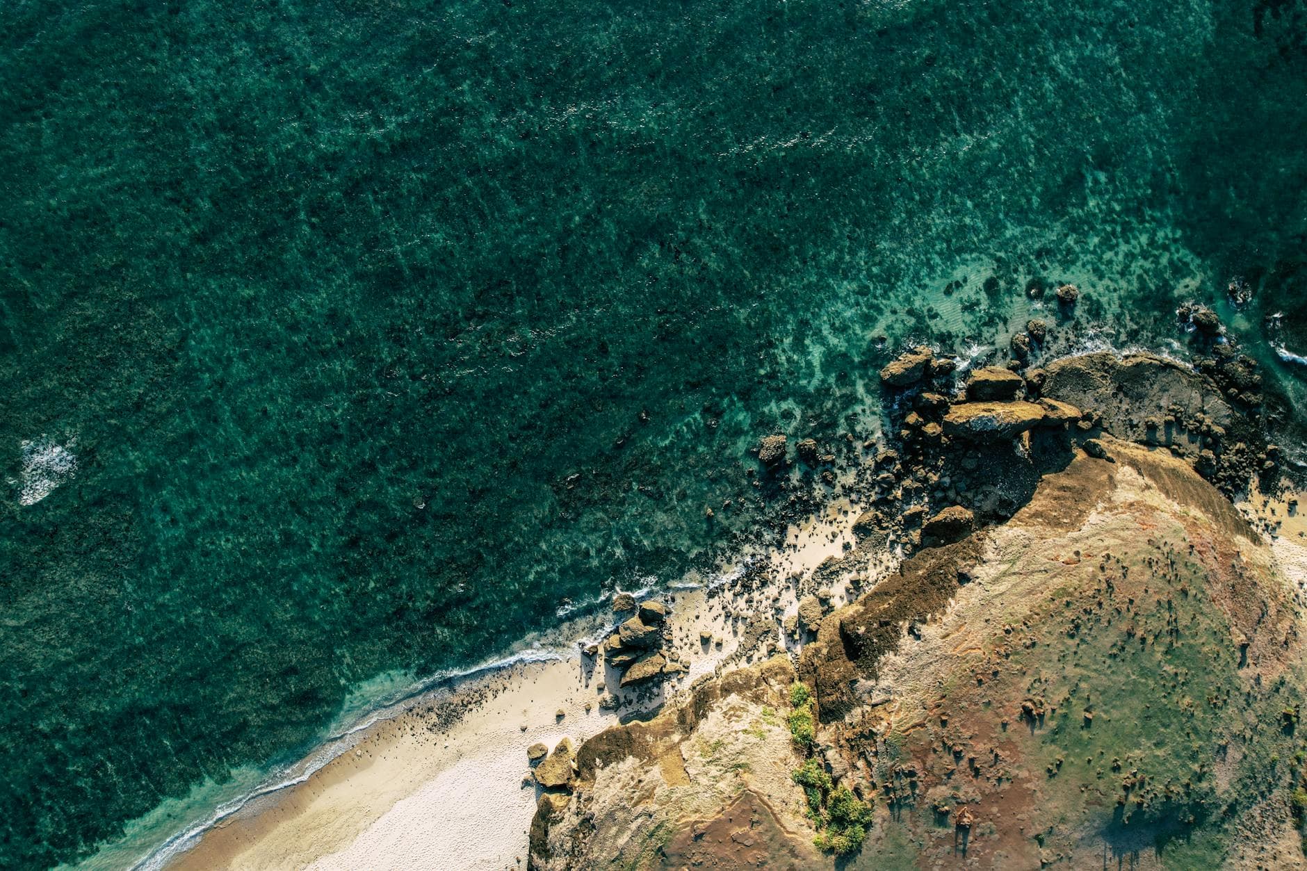 Stunning aerial shot of a rocky coastline with turquoise waters in West Nusa Tenggara, Indonesia.