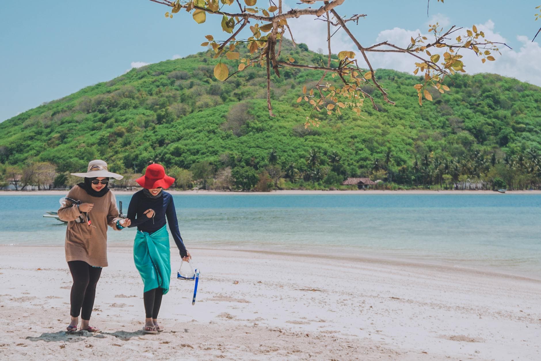 Two women strolling on a scenic tropical beach in West Nusa Tenggara, Indonesia.