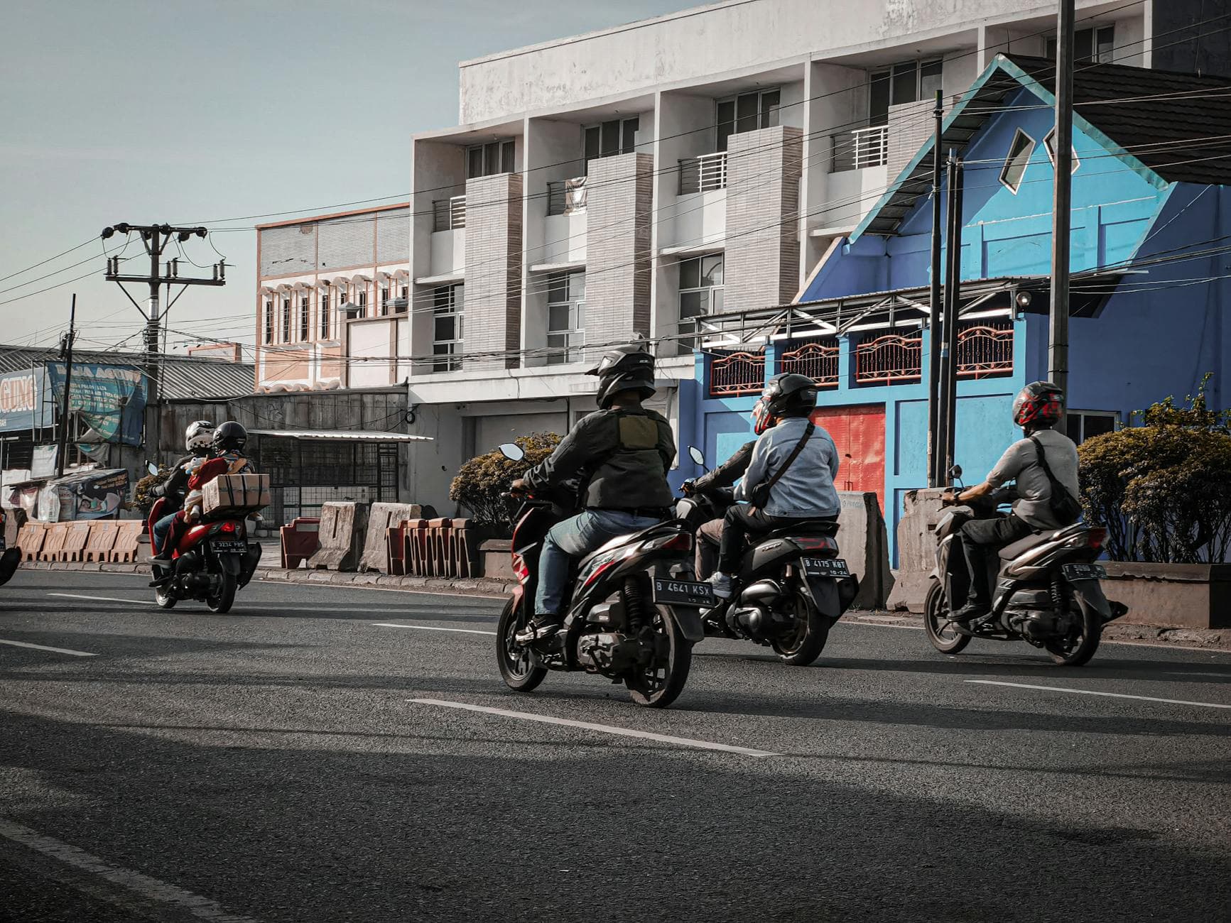 Motorcyclists commute through a busy street in an urban area of Indonesia.