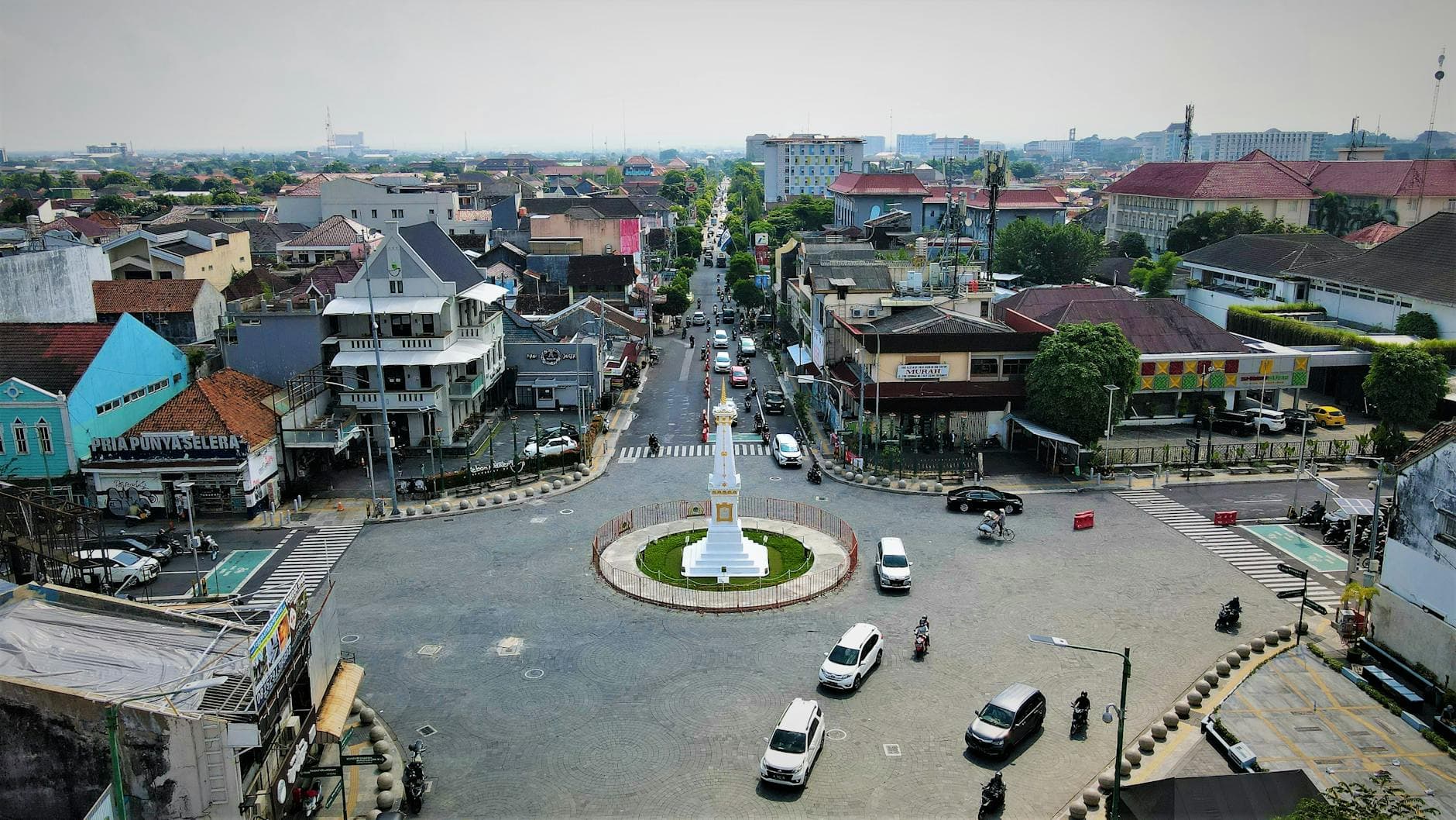Aerial view of the Tugu Yogyakarta roundabout with bustling urban traffic.