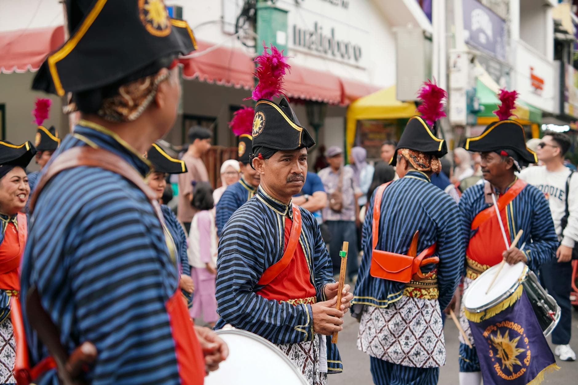 Participants in traditional attire during a cultural parade in Yogyakarta, showcasing vibrant costumes and musical instruments.