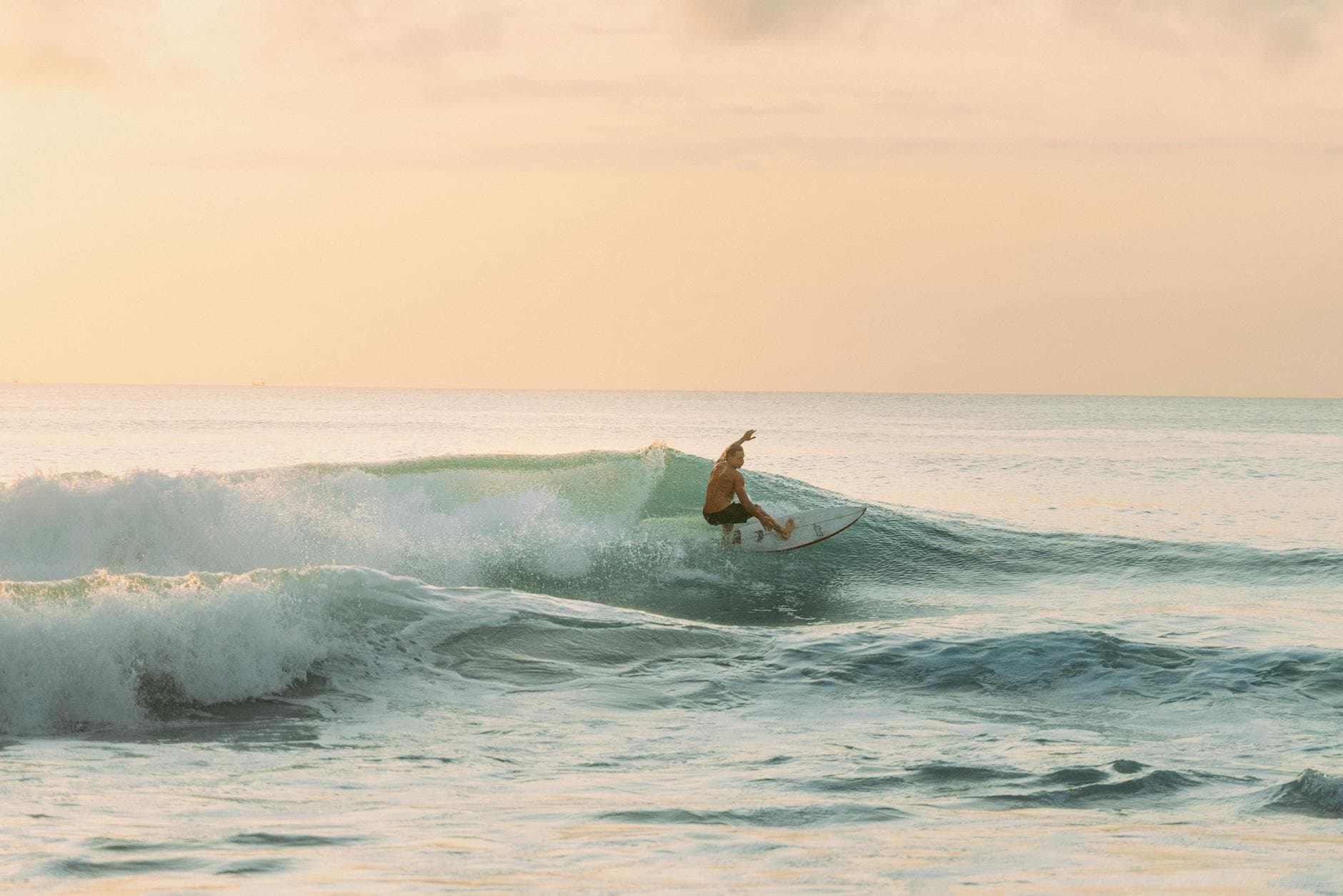A surfer catches a wave at sunset in Bali, showcasing the island's vibrant surfing culture.