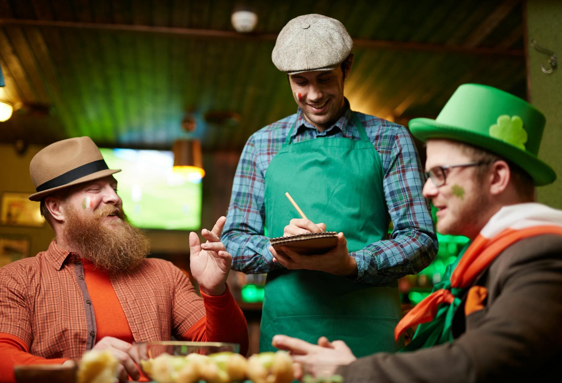 Men celebrating St. Patrick's Day with a waiter taking orders in a pub.