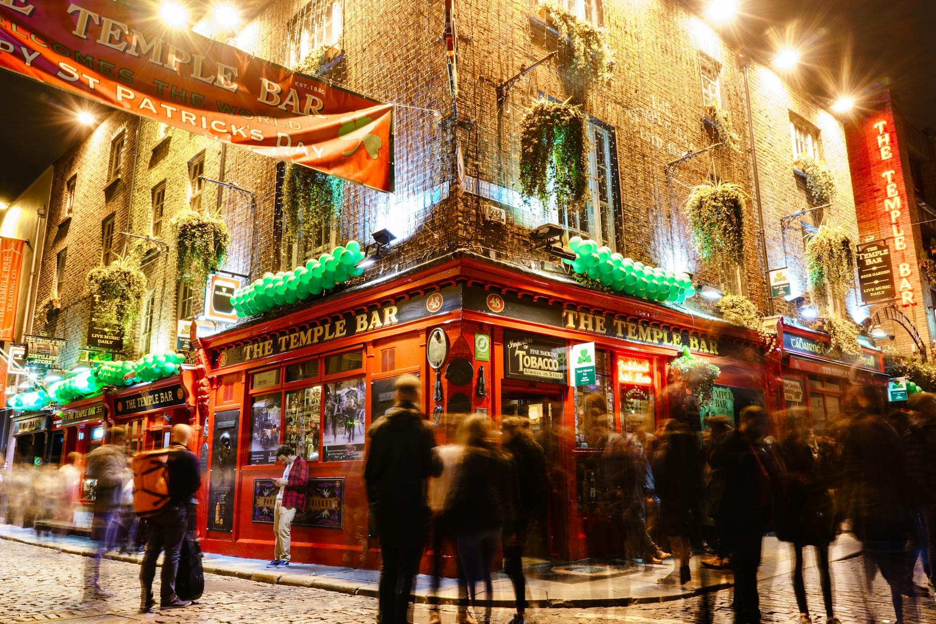 Lively night scene at the iconic Temple Bar in Dublin, showcasing St. Patrick's Day celebrations.