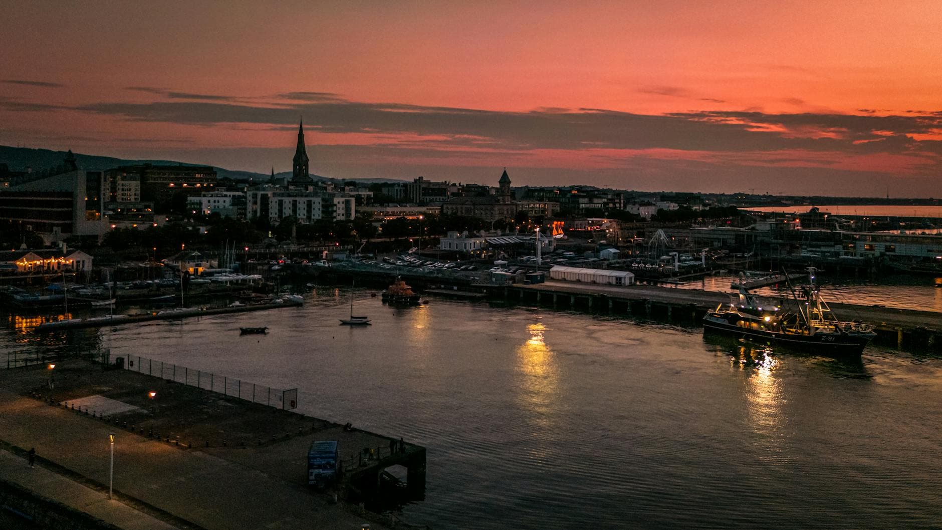A beautiful aerial view of Dun Laoghaire Harbor in Dublin, Ireland, at sunset, showcasing boats and city skyline.