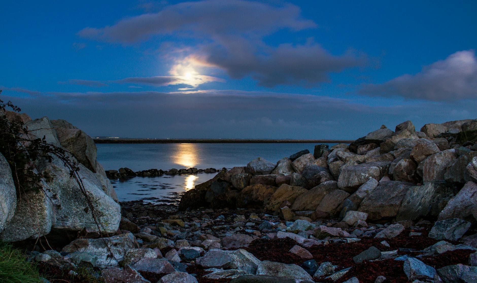 Scenic view of the moonlight reflecting on the rocky shore of Salthill, Ireland.