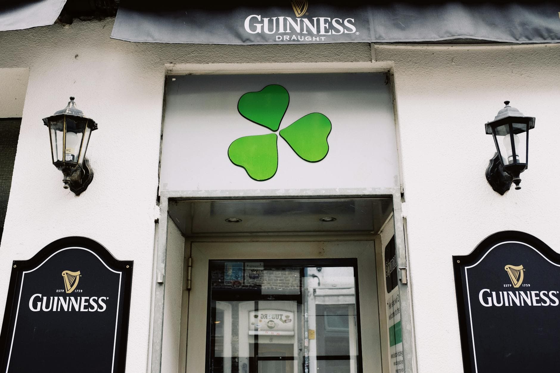 Exterior of an Irish pub with shamrock and Guinness signage, inviting visitors.