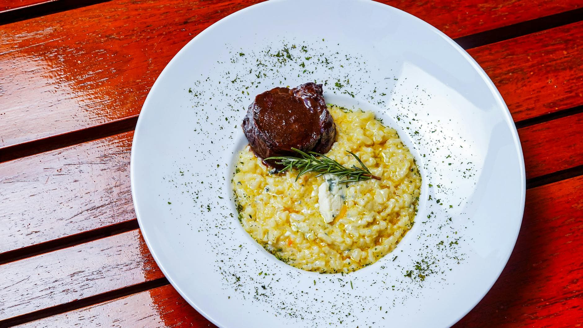 A delicious beef tenderloin served with creamy saffron risotto on a wooden table.