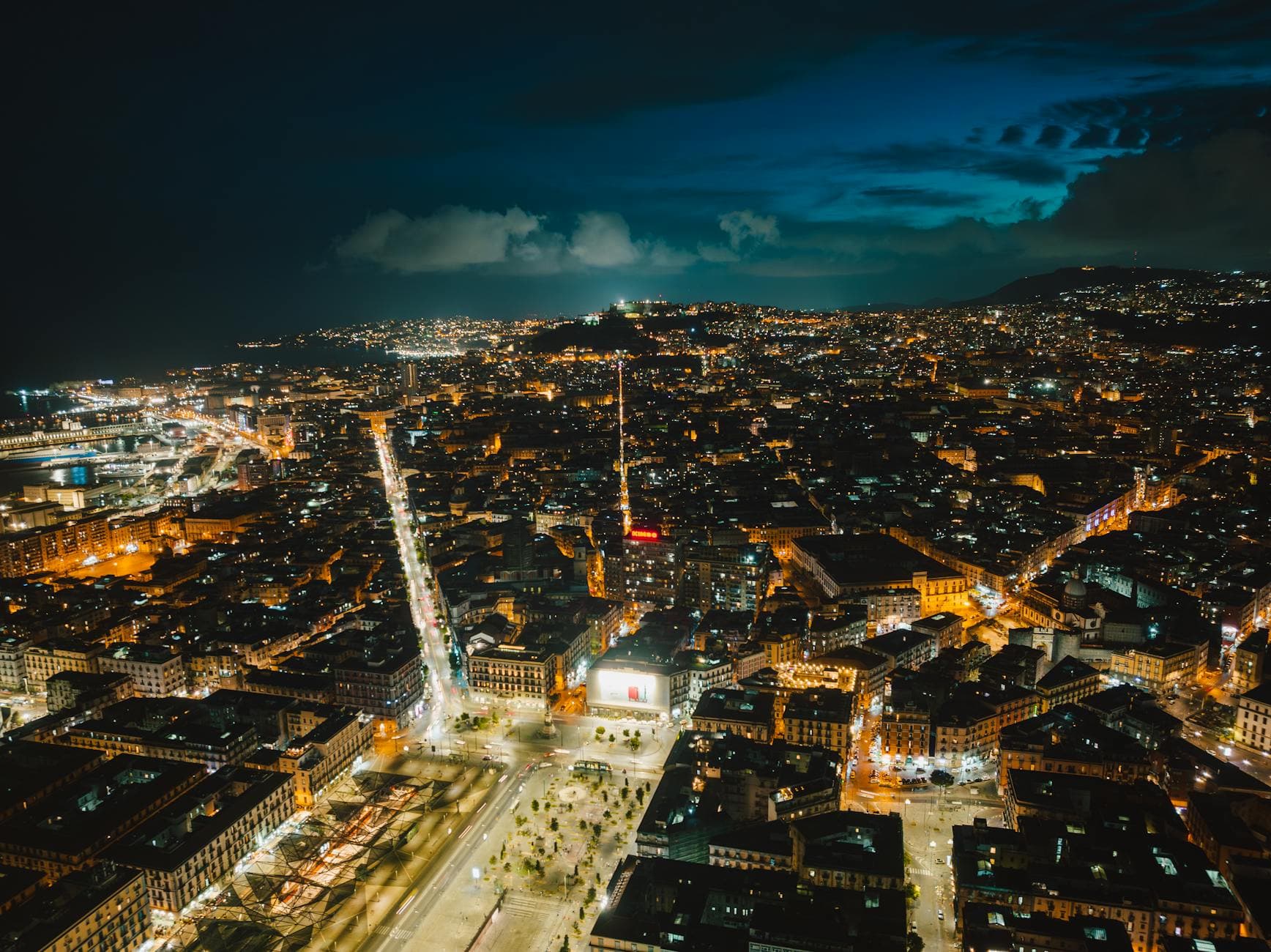 Breathtaking aerial view of Naples, Italy, illuminated at night, showcasing vibrant cityscape.