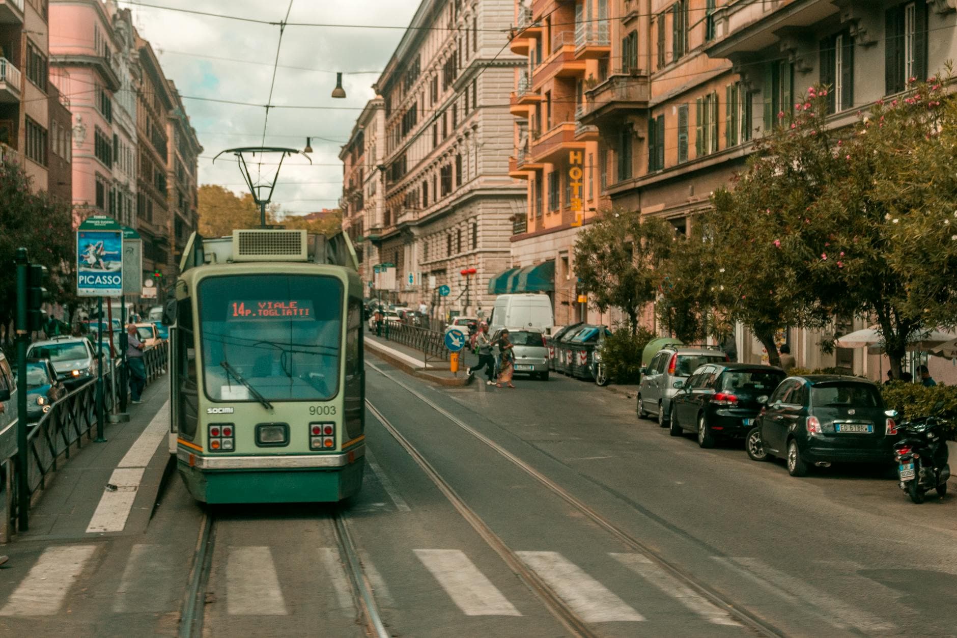 A tram travels down a busy street in Rome, Italy, surrounded by classic architecture.